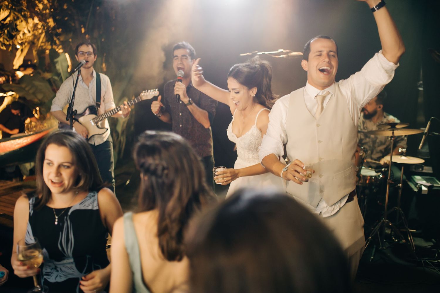 Wedding celebration with live band performing while guests dance energetically on the dance floor.