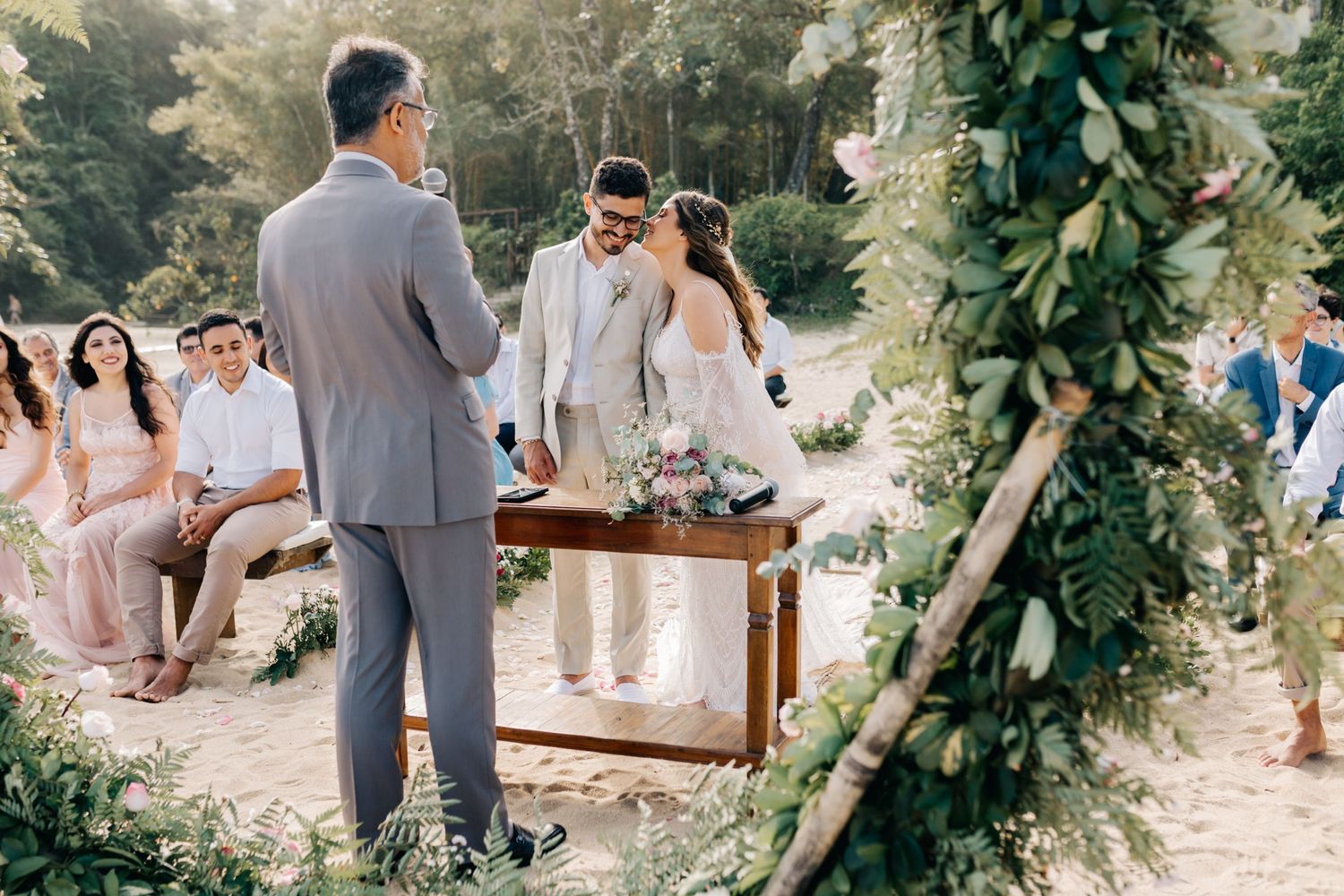 Wedding ceremony space decorated with flowing greenery and rustic wooden seating.