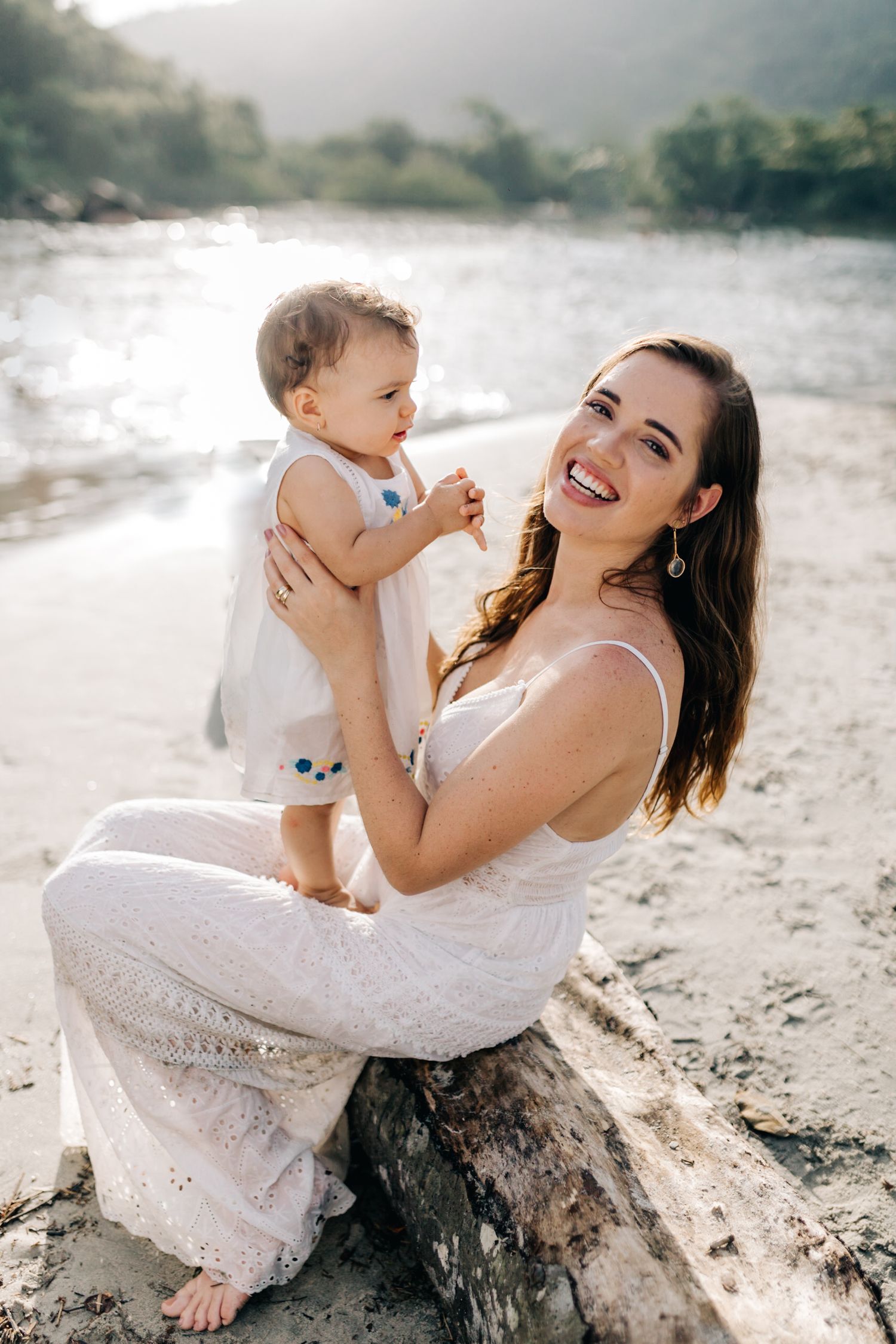 Candid laughter and joy shared between parent and toddler on a beach log.