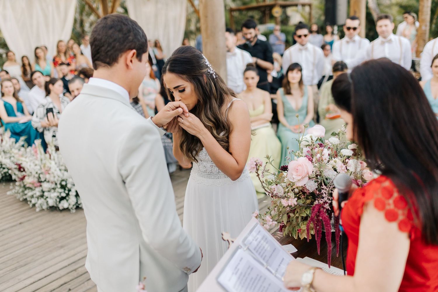 Emotional wedding ceremony moment during vows on decorated wooden deck.