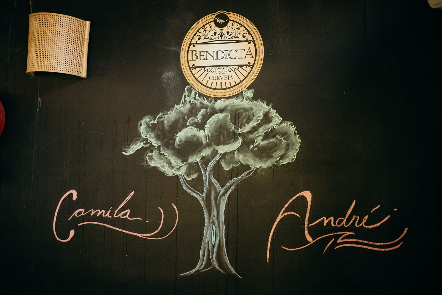A detailed chalk drawing of a tree with cursive text and a circular logo on a dark wall.