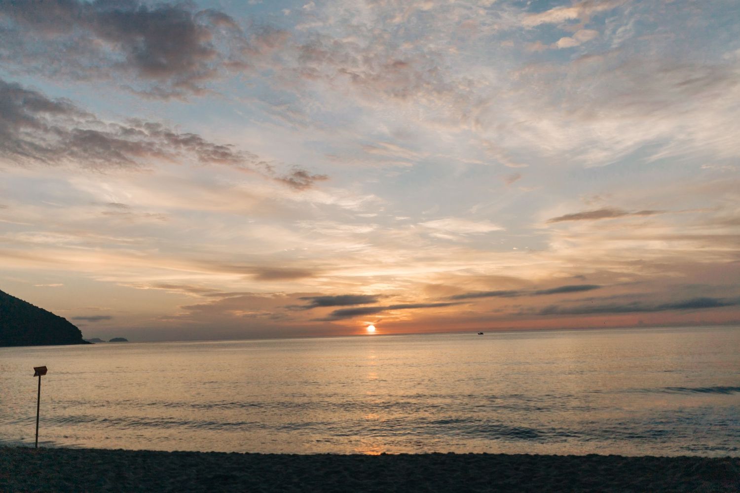 A breathtaking ocean sunset with pink and orange clouds reflecting on calm waters.