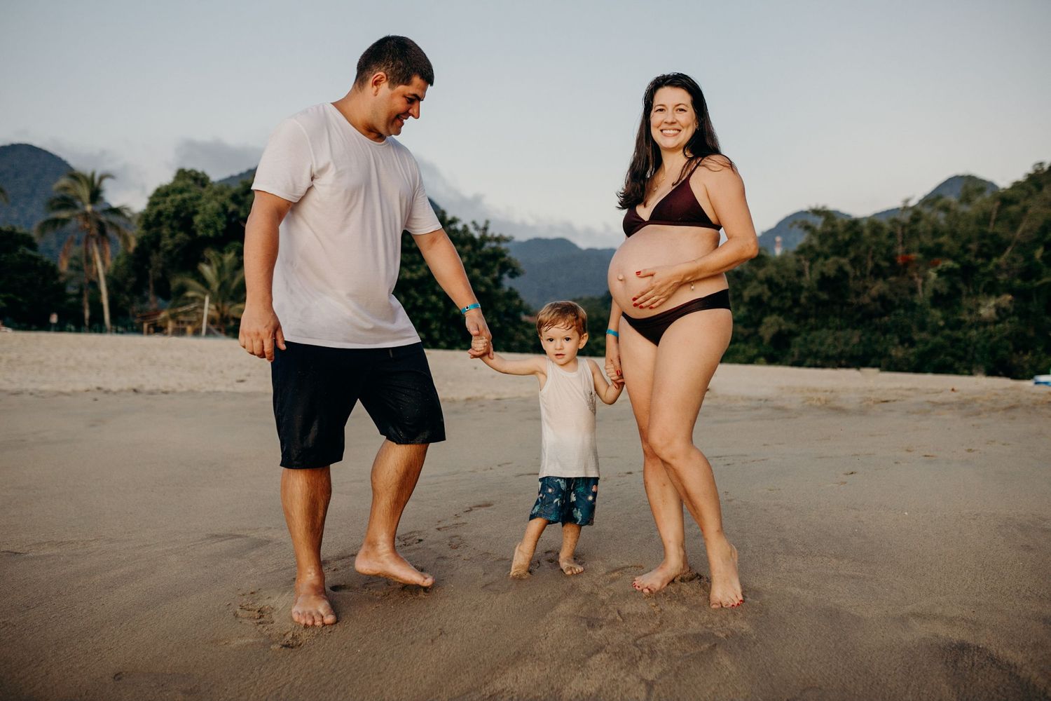 Family playing together on a scenic beach with mountains in the background.