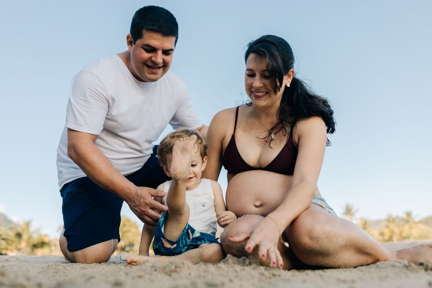 Family members share laughter and smiles while sitting together on a sandy beach.