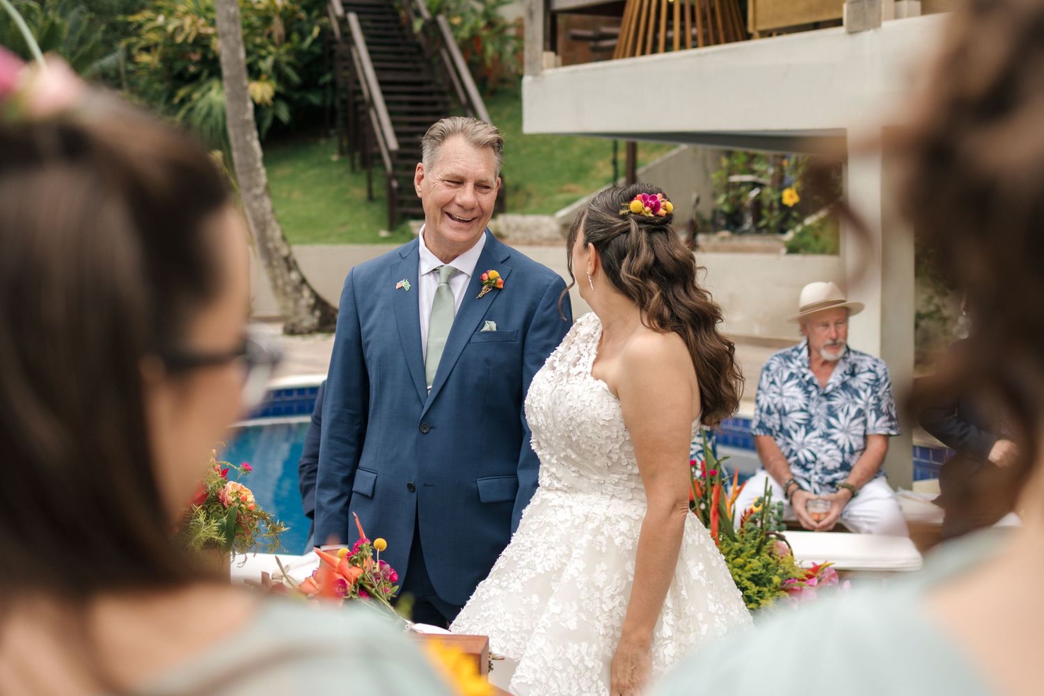 Outdoor wedding ceremony setup with guests seated in chairs and colorful floral decorations.