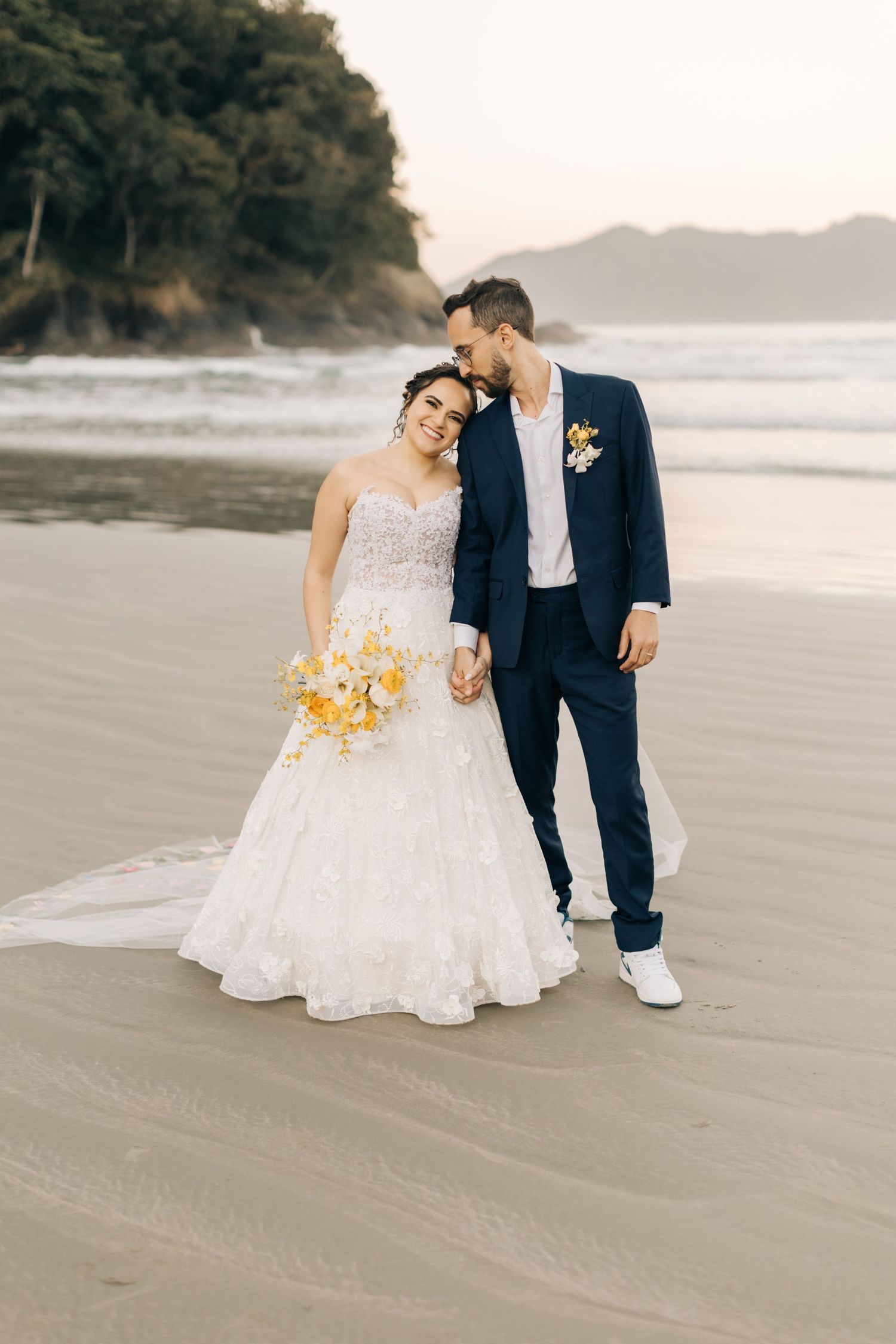 Romantic beach wedding portraits featuring a white dress and navy suit against a scenic coastal backdrop.