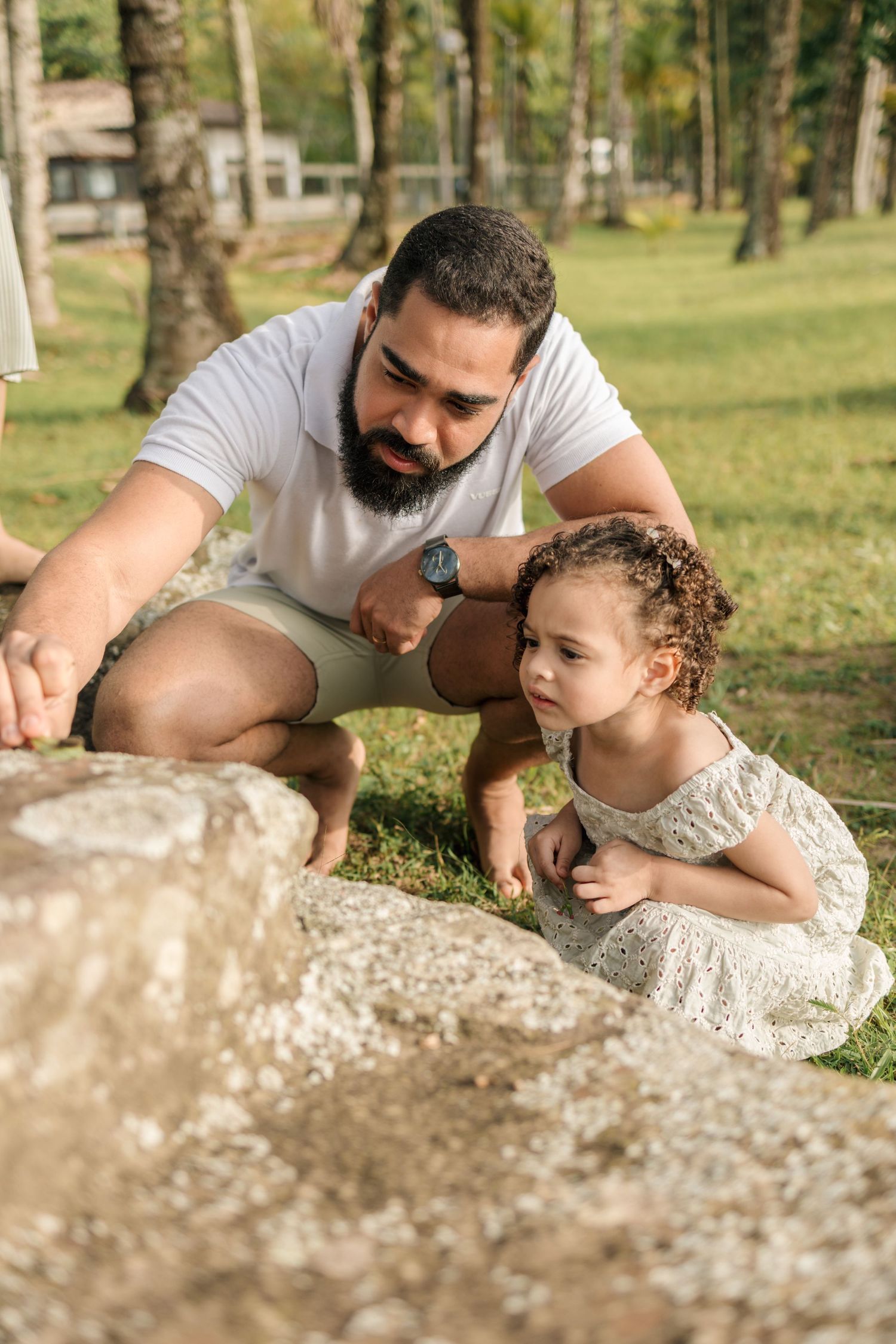 A sequence of photos showing a parent and child lying on the ground examining something together in a park setting.