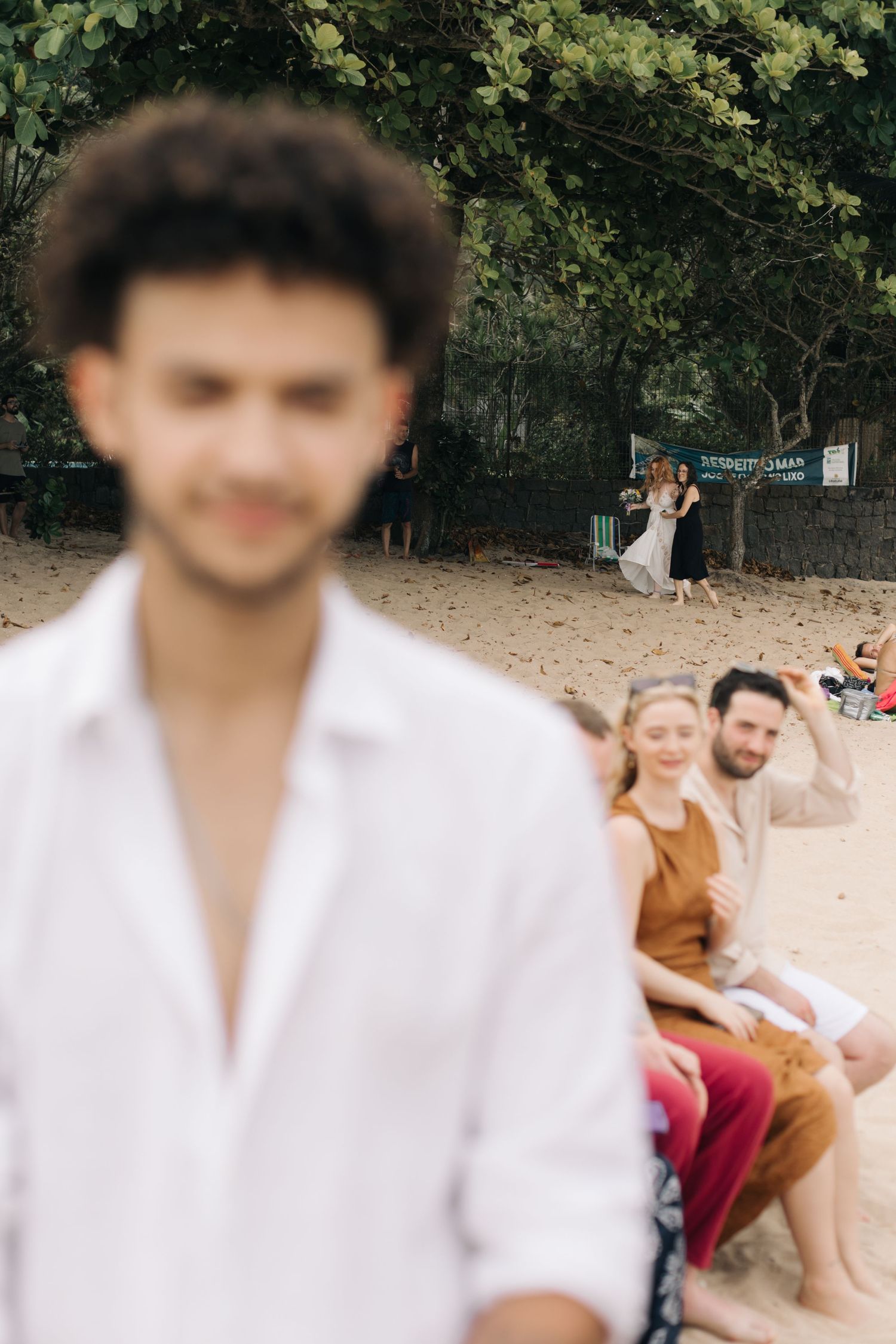 Candid beach wedding moment with guests gathered on sandy shore.