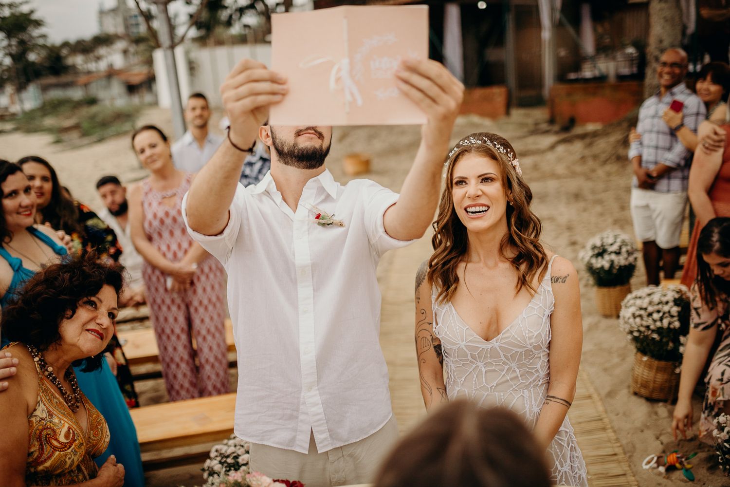 A celebratory moment during a beach wedding ceremony with guests looking on.