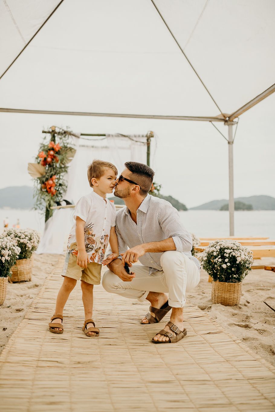 Close-up of bare feet on wooden planks at a beach wedding celebration.