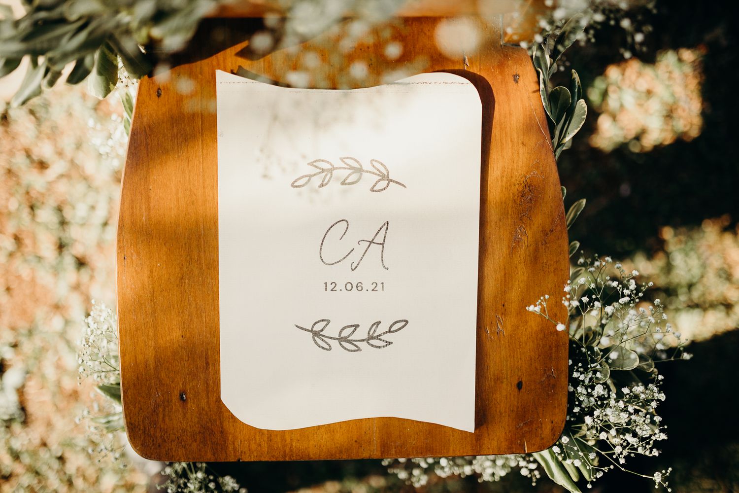 Close-up of wedding monogram card surrounded by floral arrangements.