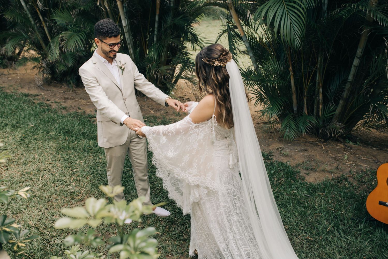 A couple dances together in their wedding attire surrounded by palm trees and tropical foliage.