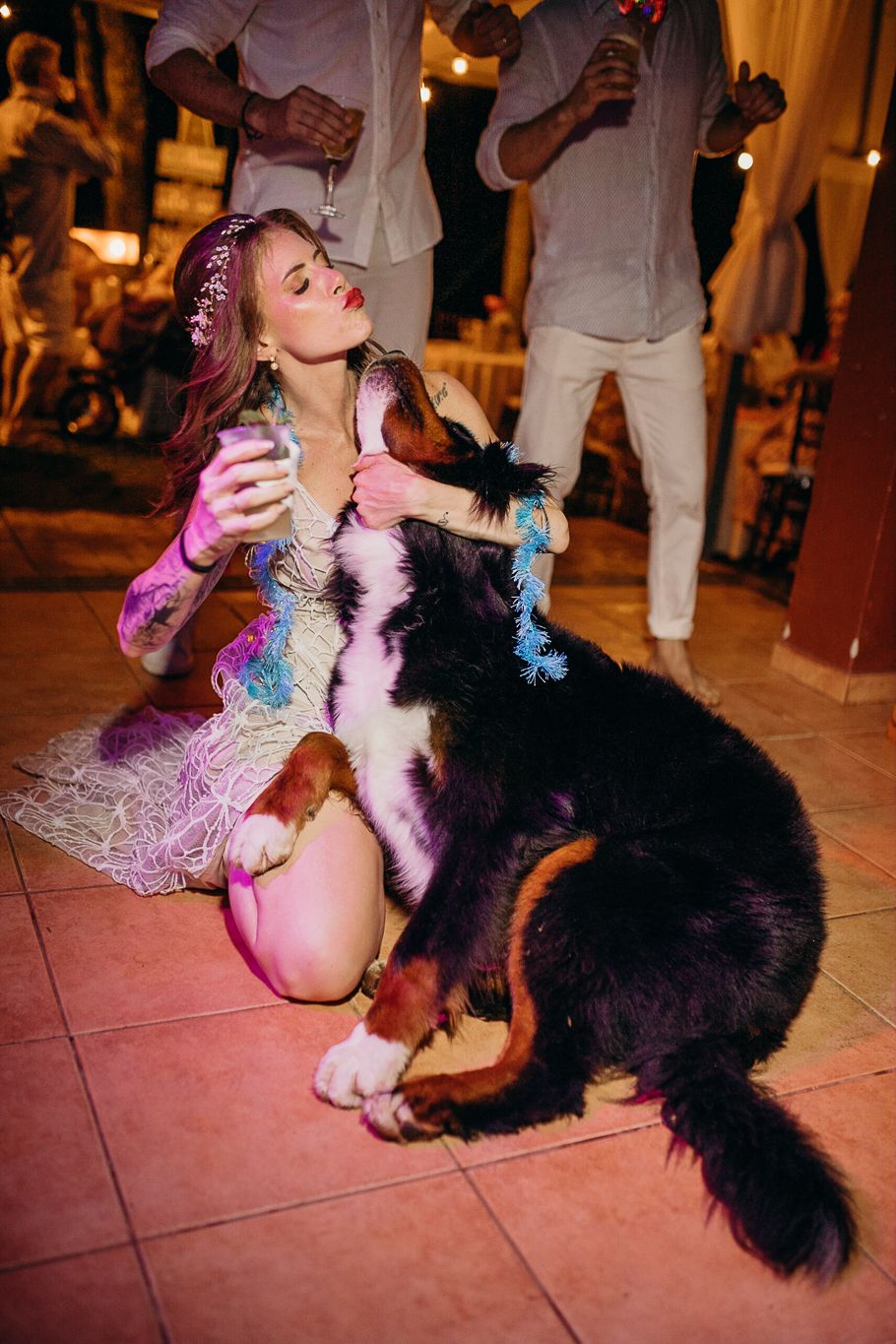 Energetic dog jumping up to greet someone in a light-colored party dress on a tiled floor.