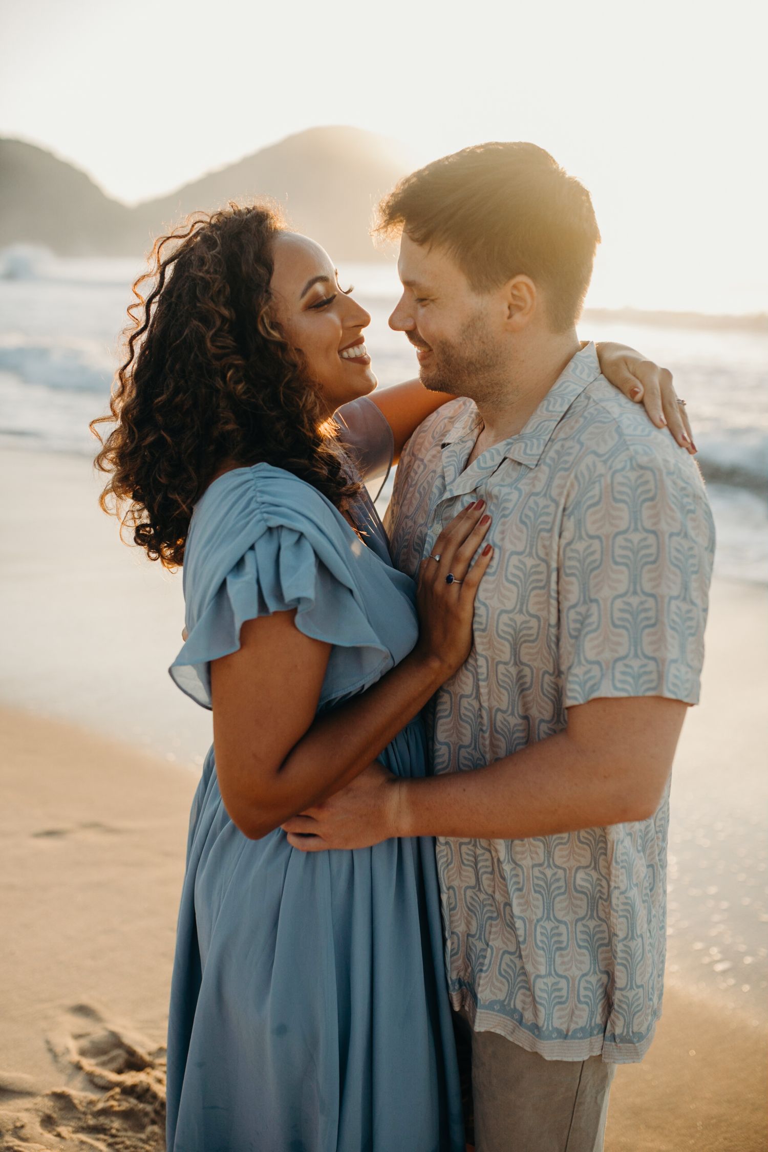 Loving couple sharing tender moment on beach with sunset glow.