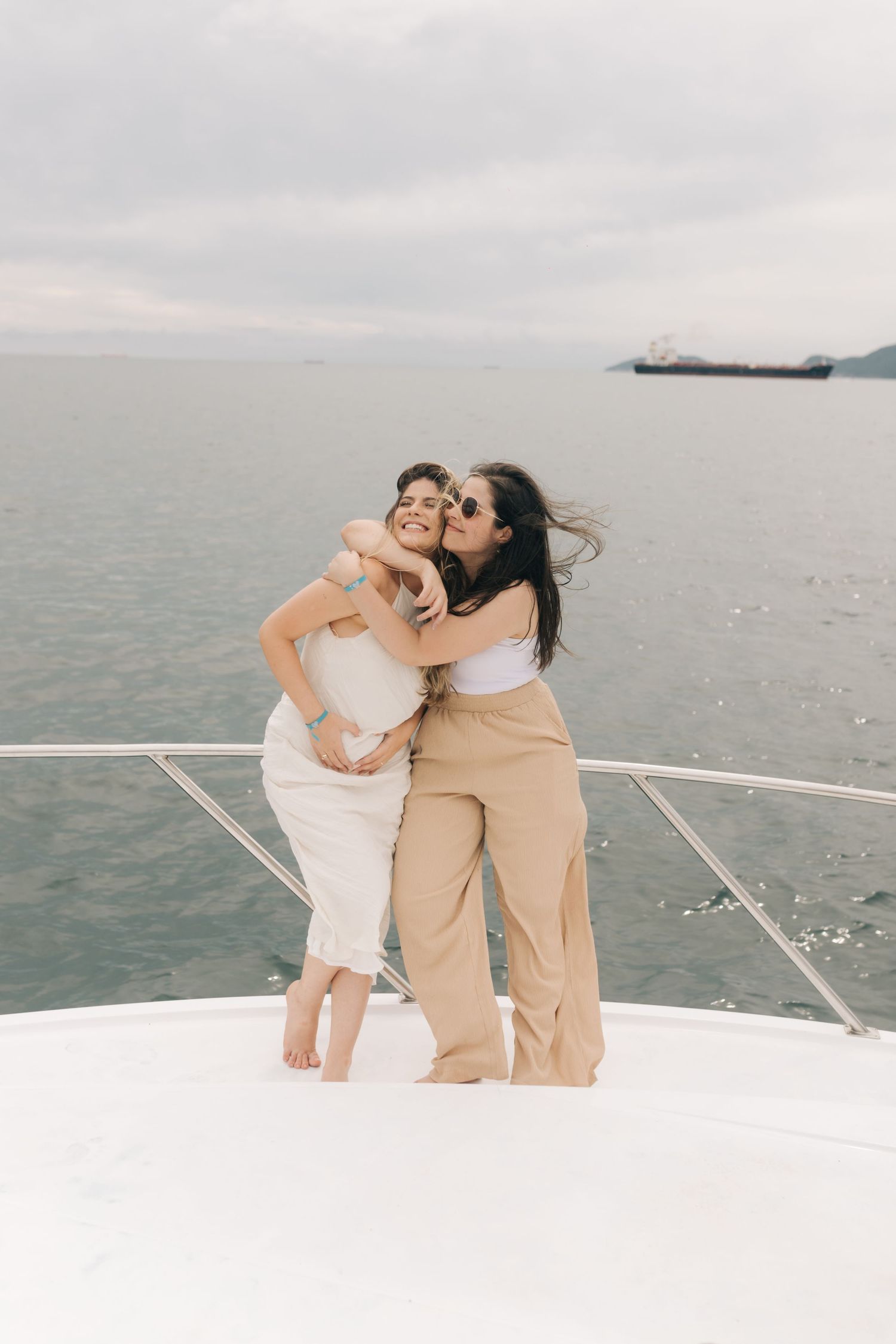 Two people share a warm embrace on a boat deck against a cloudy seascape.