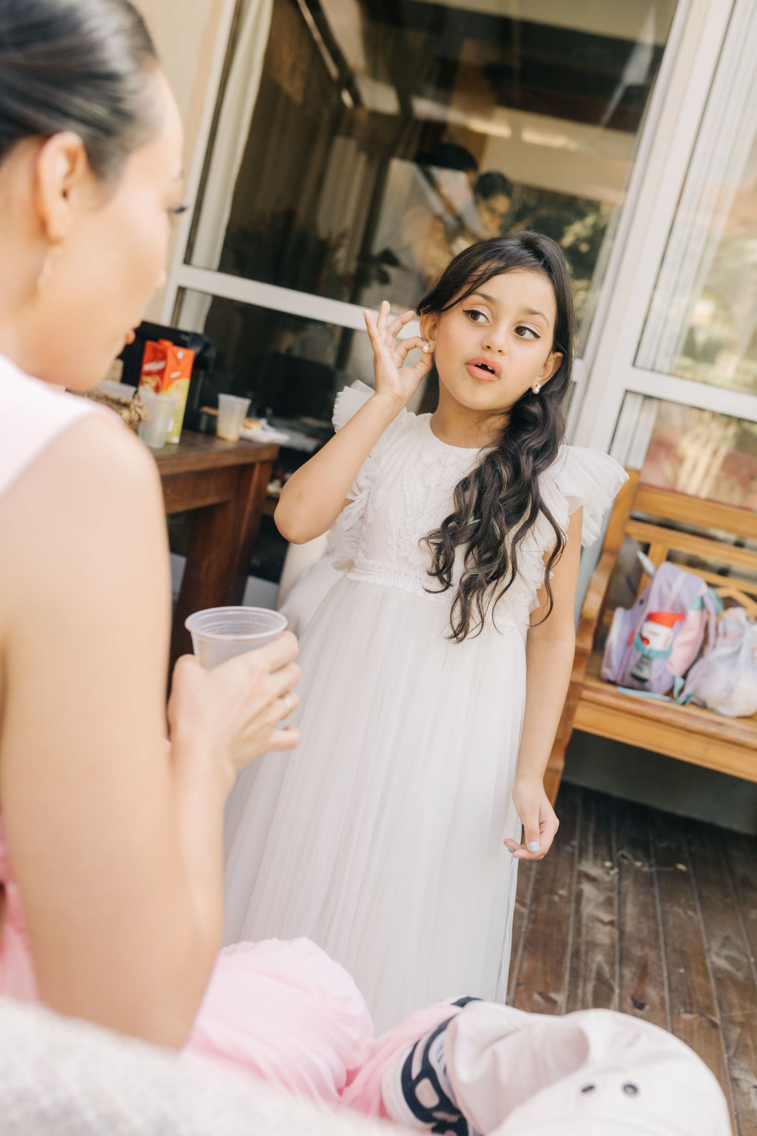 Young attendant in white dress getting ready during wedding preparations.
