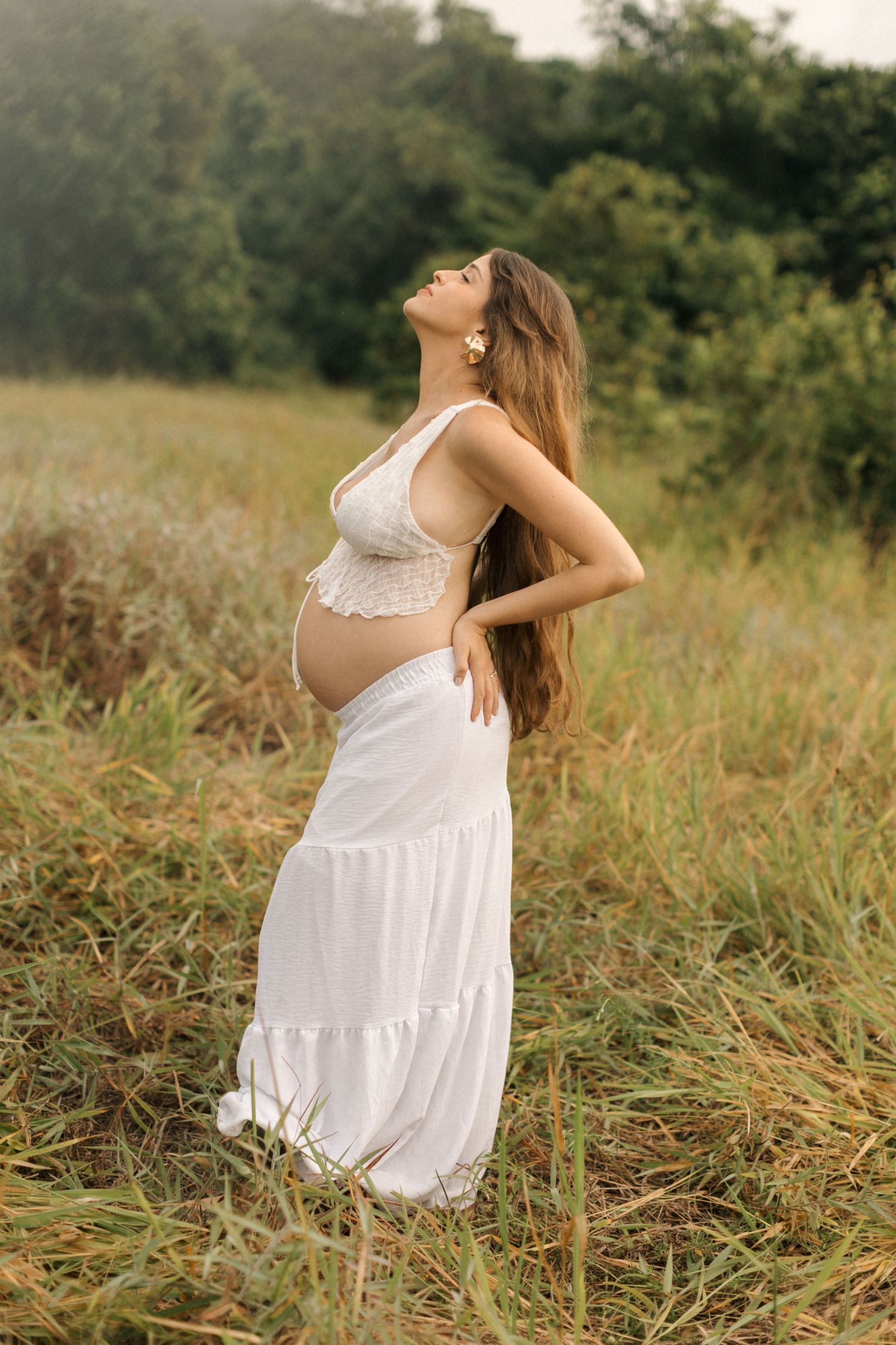 Woman in white dress twirling gracefully in a sunlit meadow during golden hour.