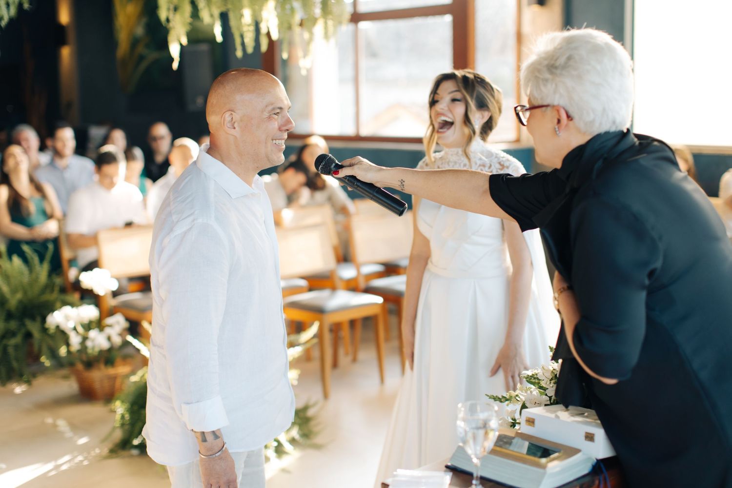 Wedding ceremony moment with officiant and couple in white attire.