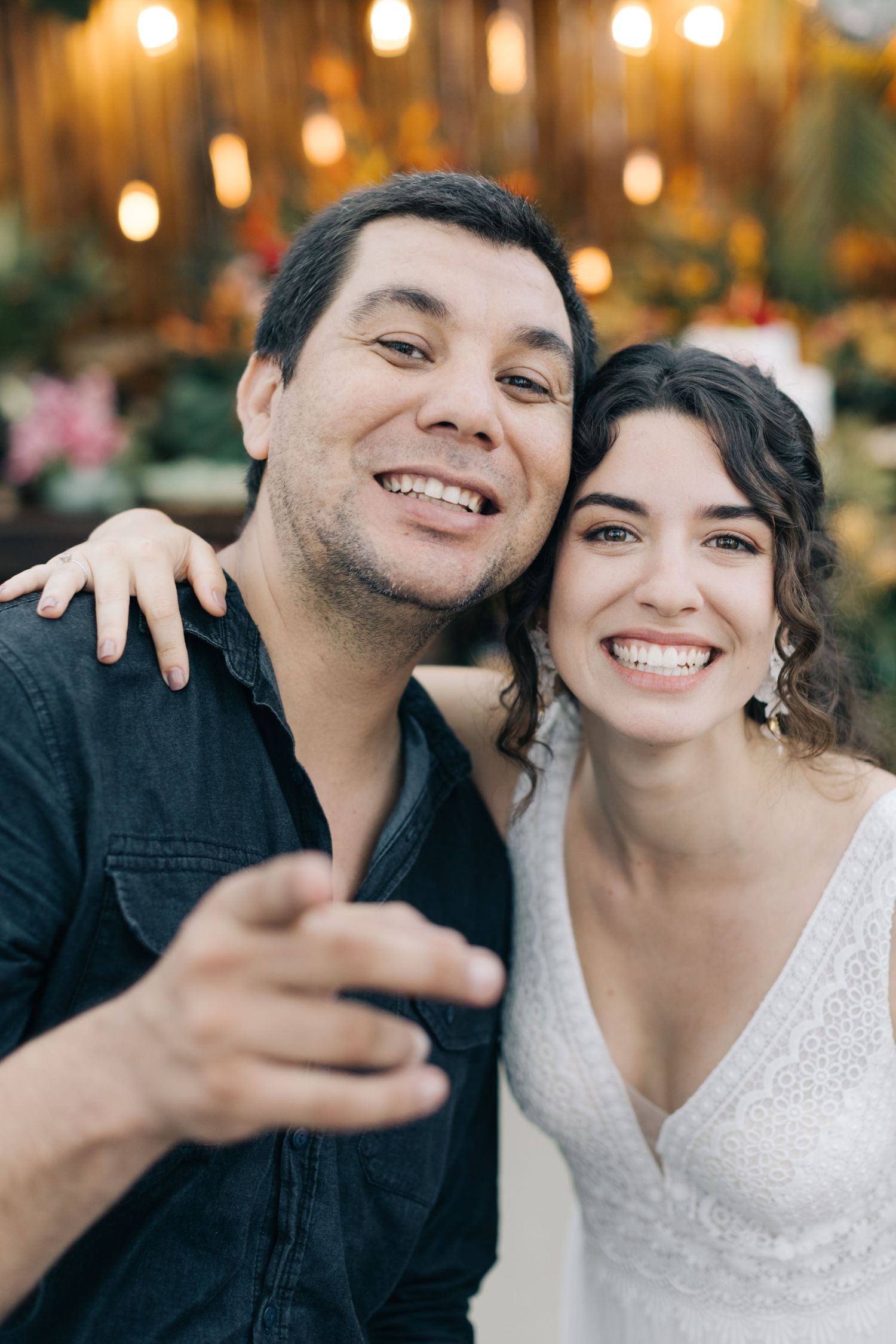 A couple celebrates their wedding day with joyful expressions in front of tropical decor.