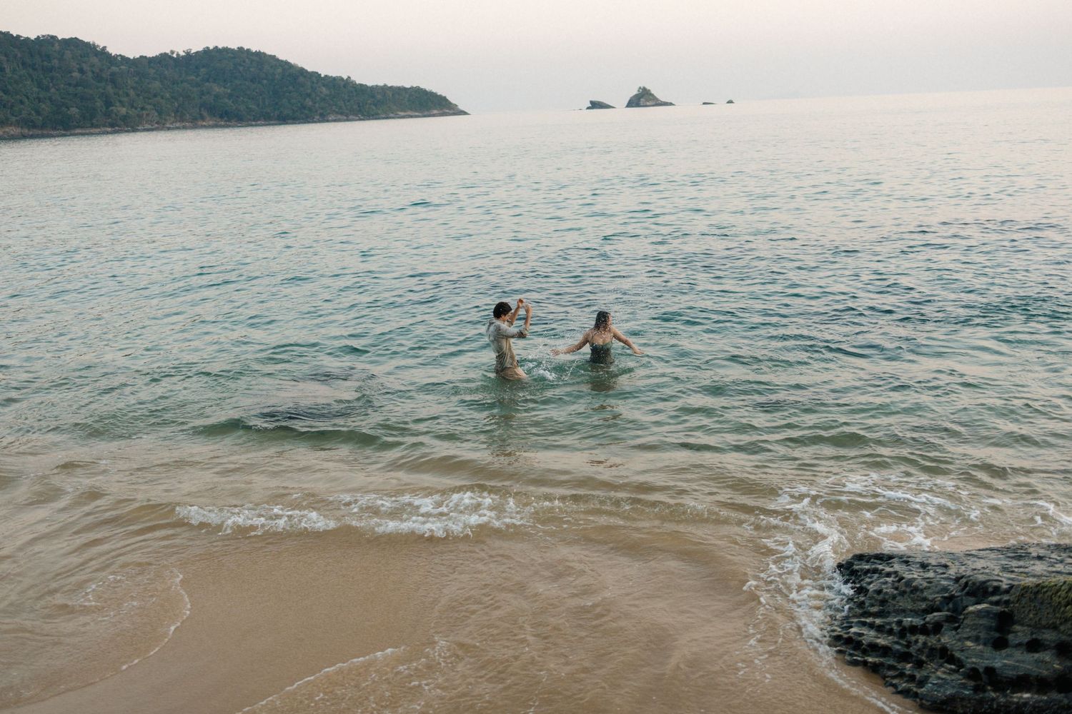 Two people enjoying the ocean waters during a serene sunset.