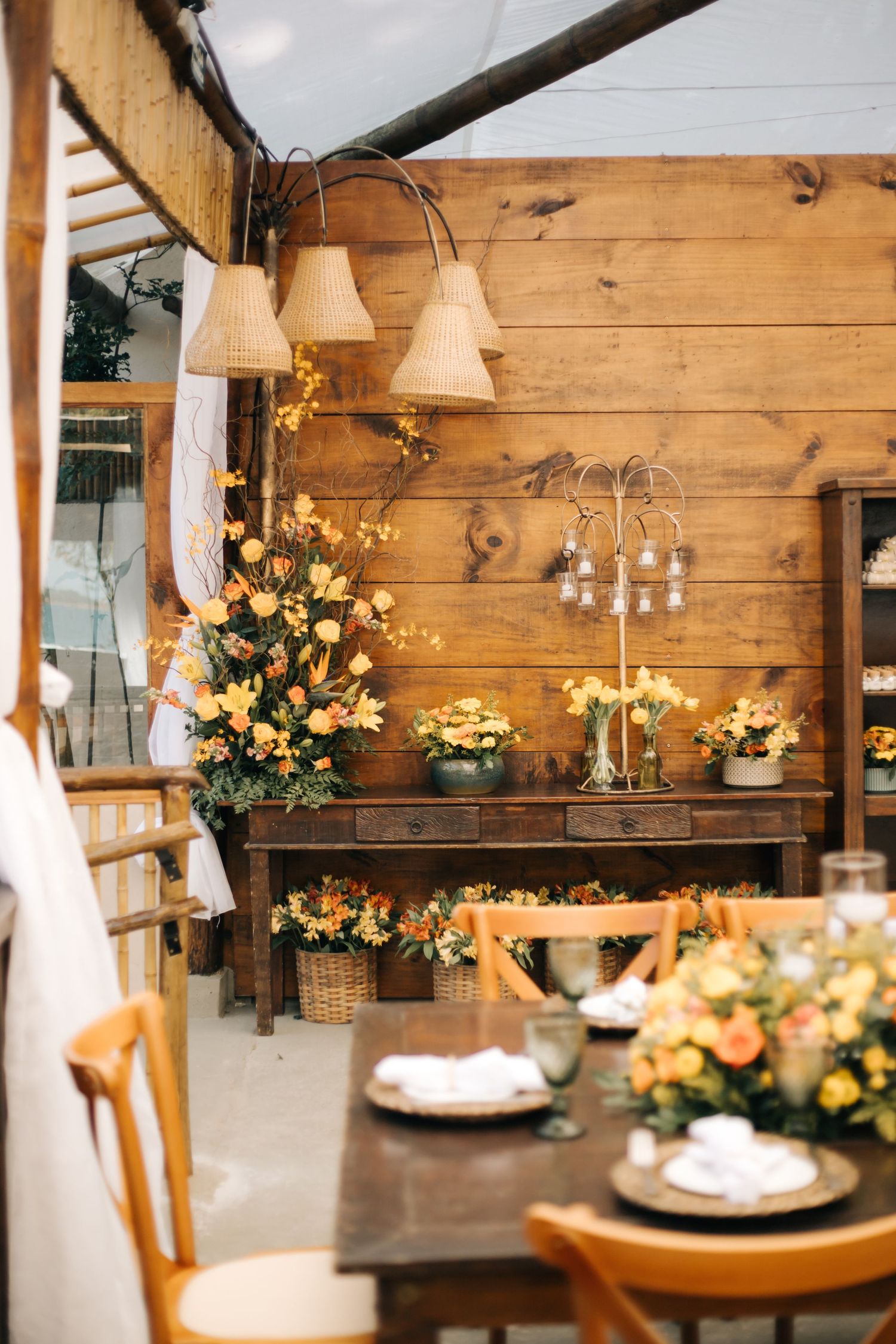 Rustic wooden wedding venue decorated with yellow floral arrangements and ambient lighting.