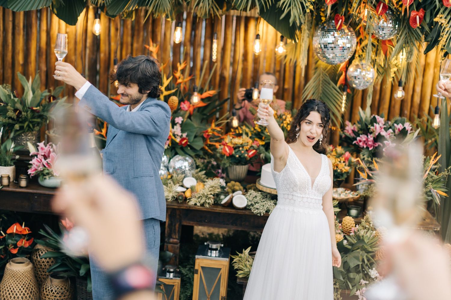 Celebratory moment at wedding reception with palm leaves and disco ball decor.