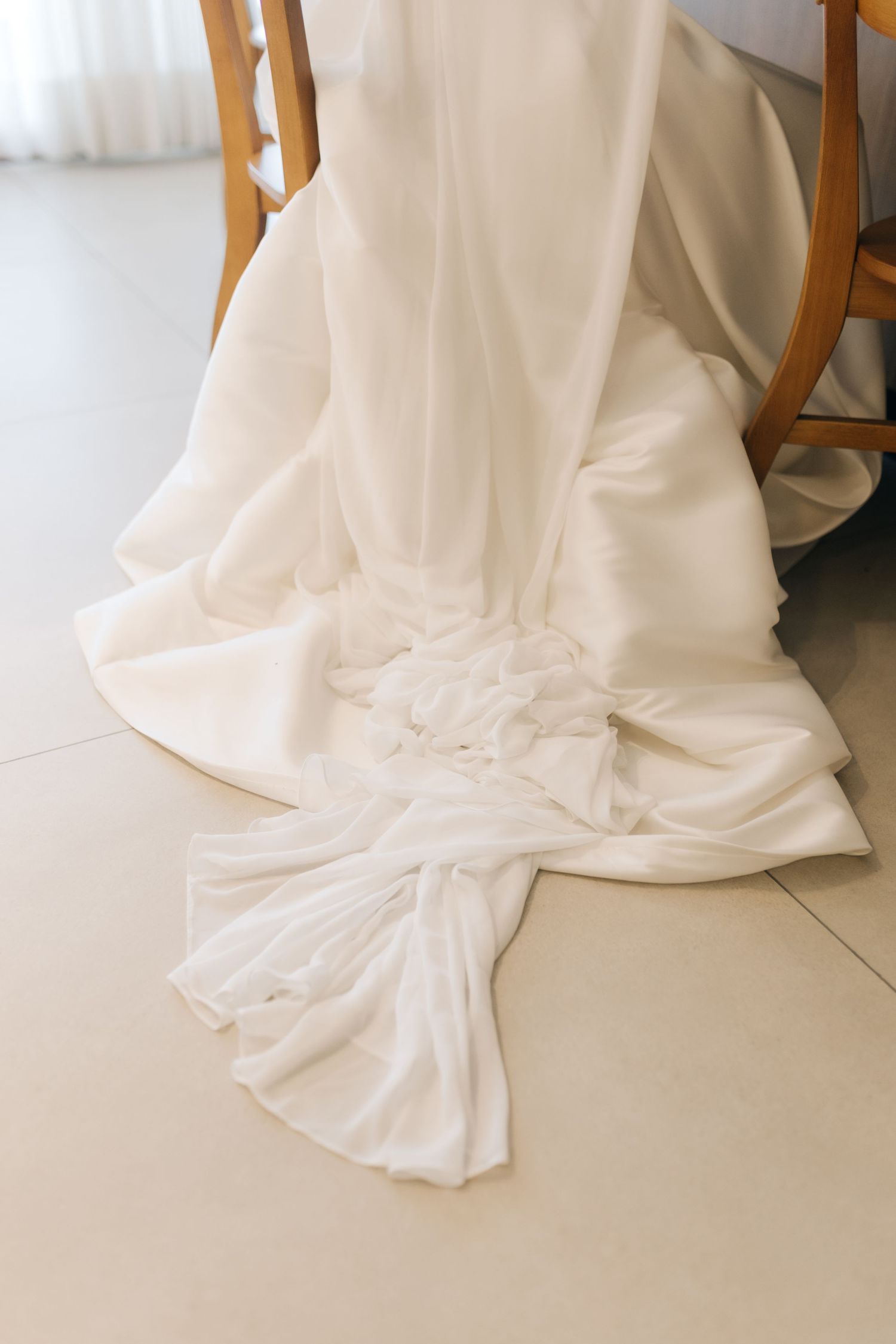 Detail shot of white wedding dress train pooled on light colored floor.
