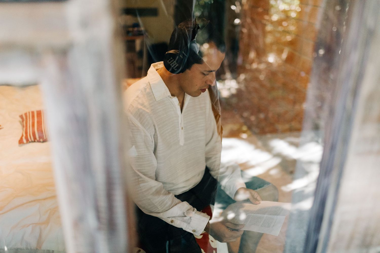 Someone wearing a white henley shirt and headphones works diligently on a project.