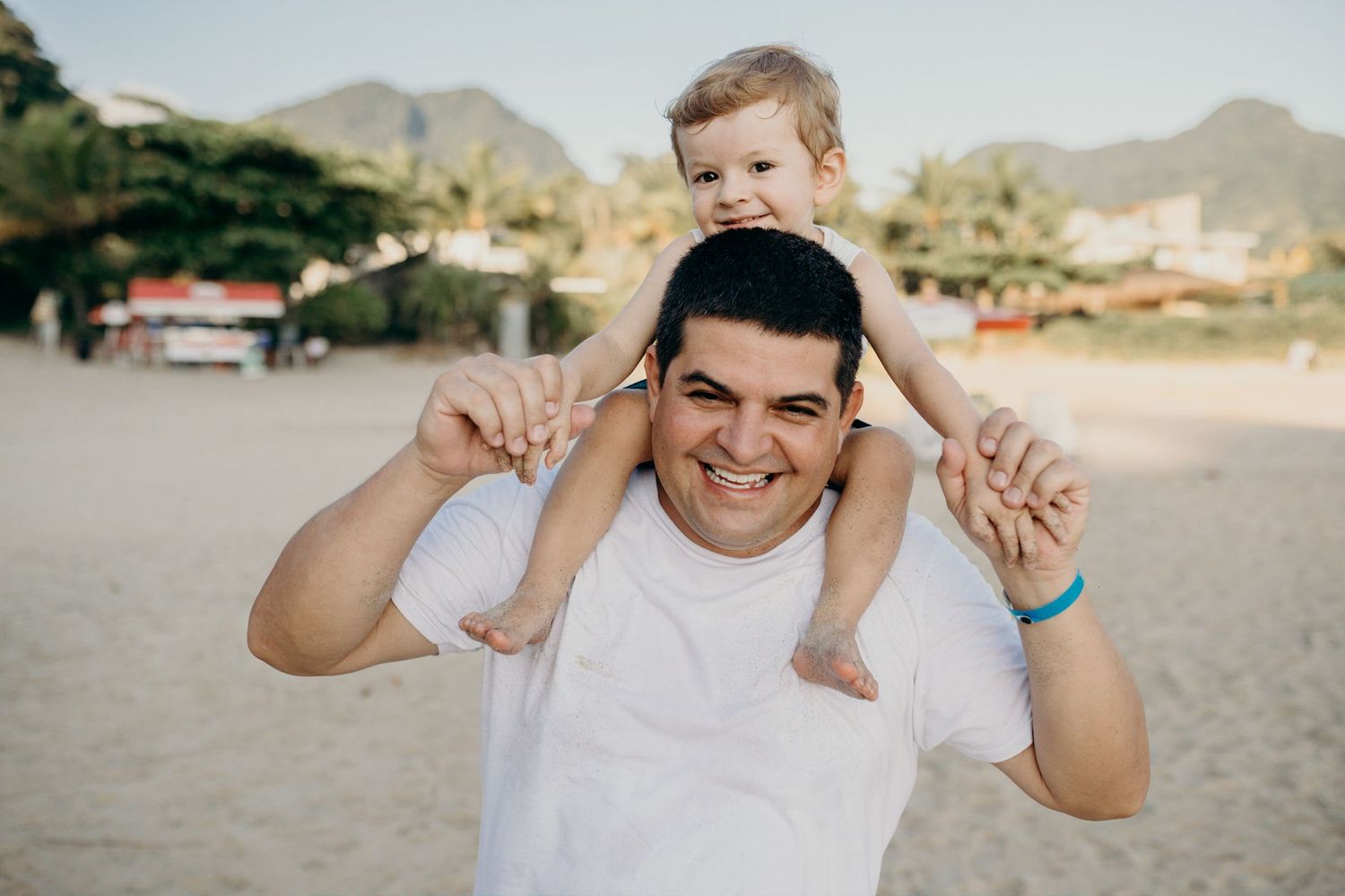 Playful moment captured on a sunny beach with mountains in the background.