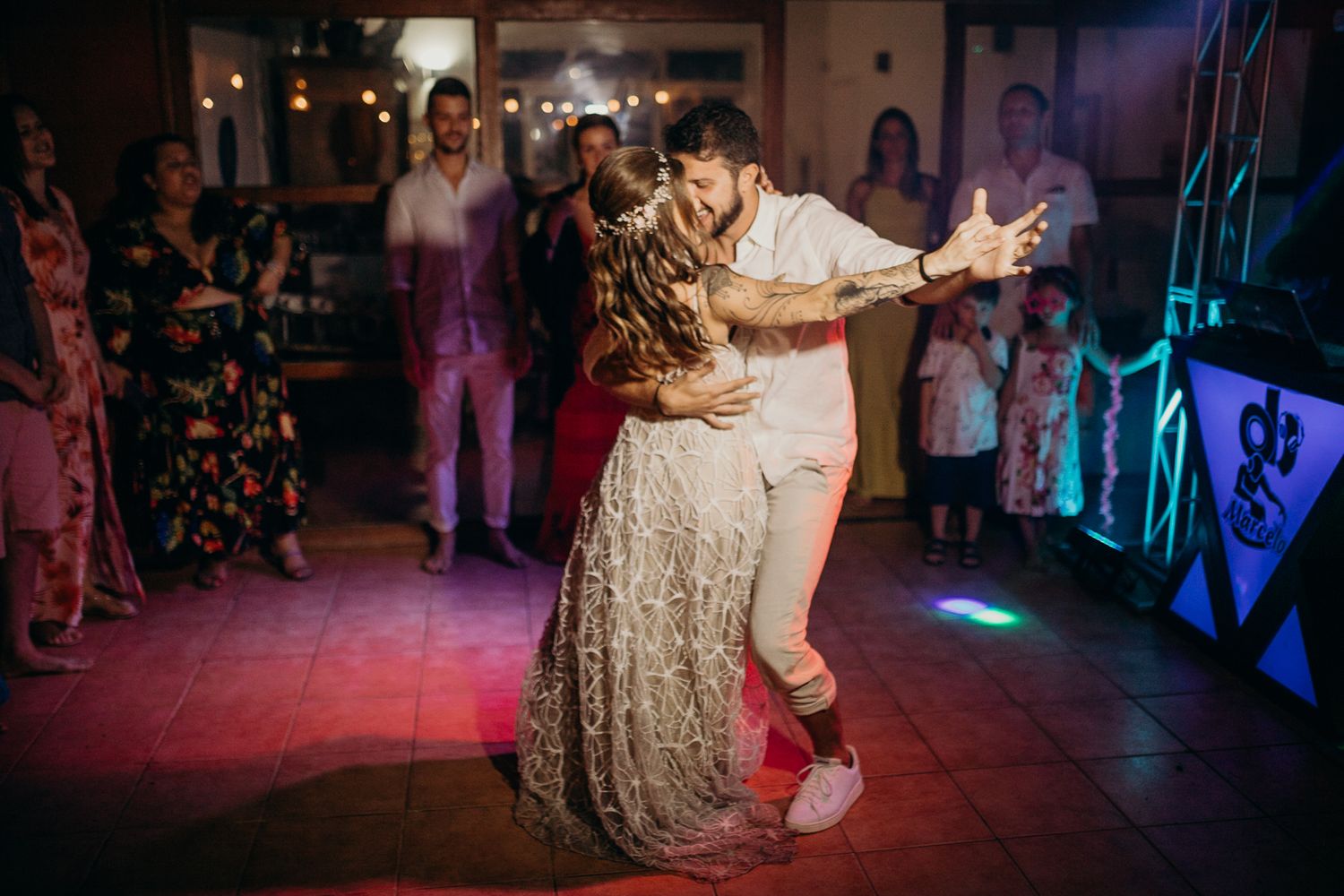 Wedding guests performing choreographed dance moves under atmospheric purple lighting.