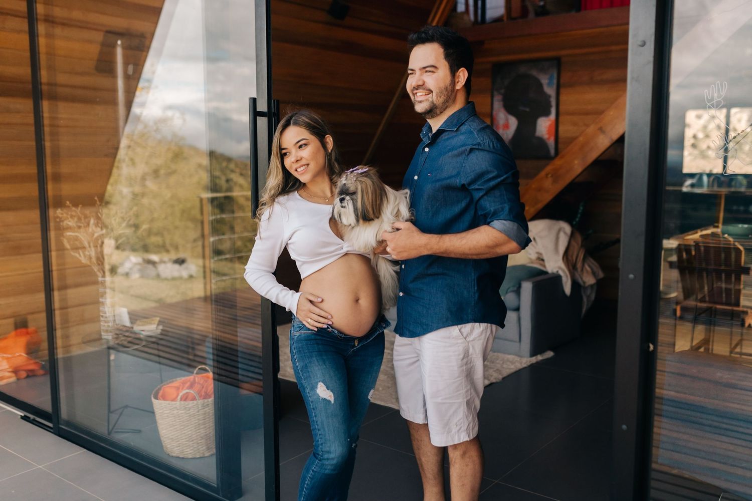 Intimate maternity photoshoot on a rustic deck with a cozy blanket and mountain views in the background.