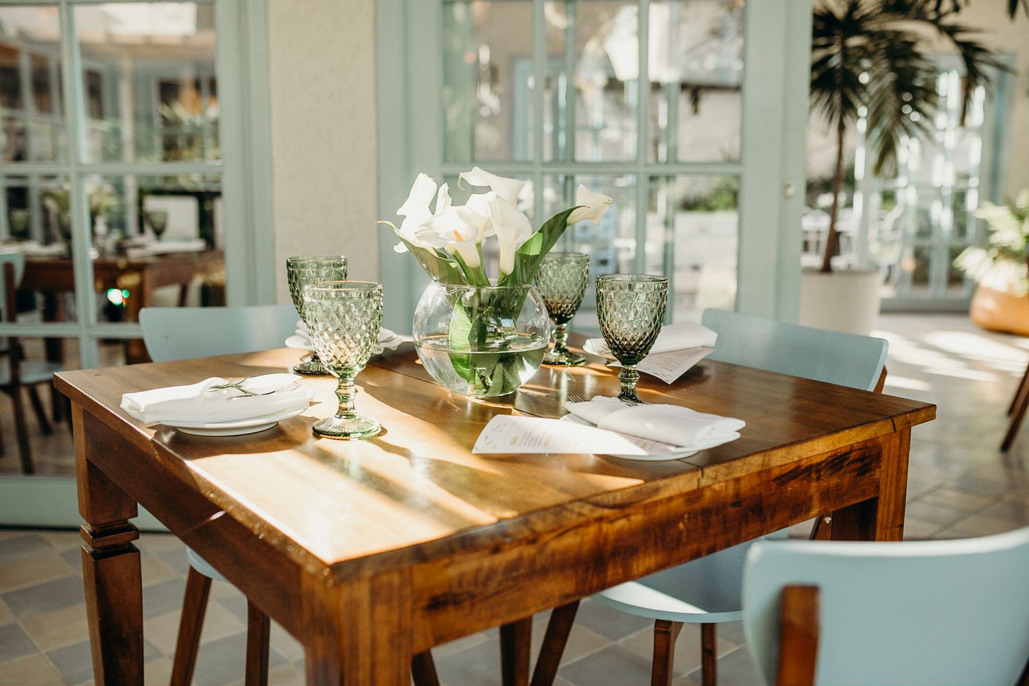 Rustic wooden dining tables arranged in a bright, airy restaurant space.