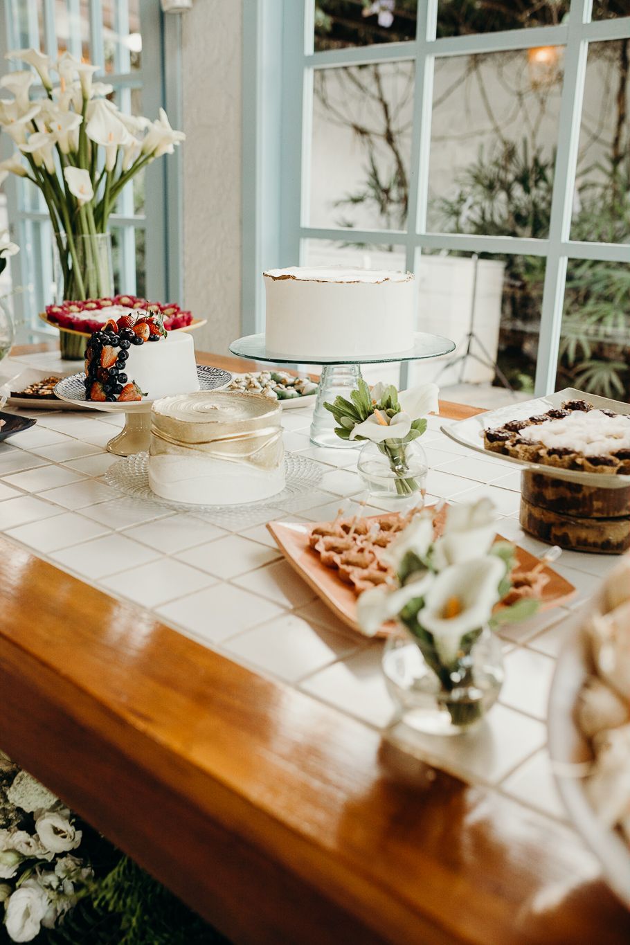 Catering display featuring desserts and appetizers on a wooden table with white floral accents.