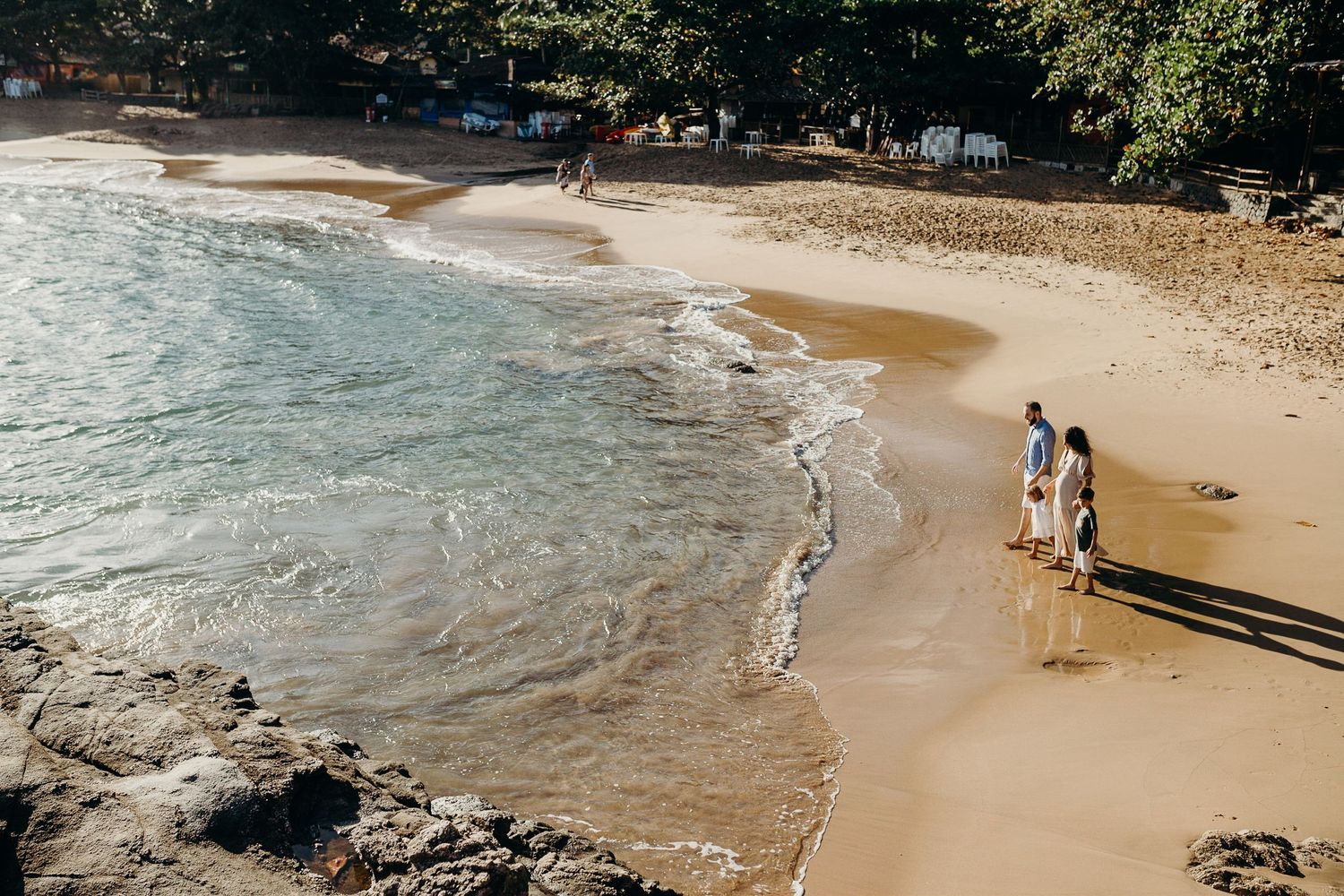 Scenic beach landscape with waves crashing against rocks and sandy shoreline.