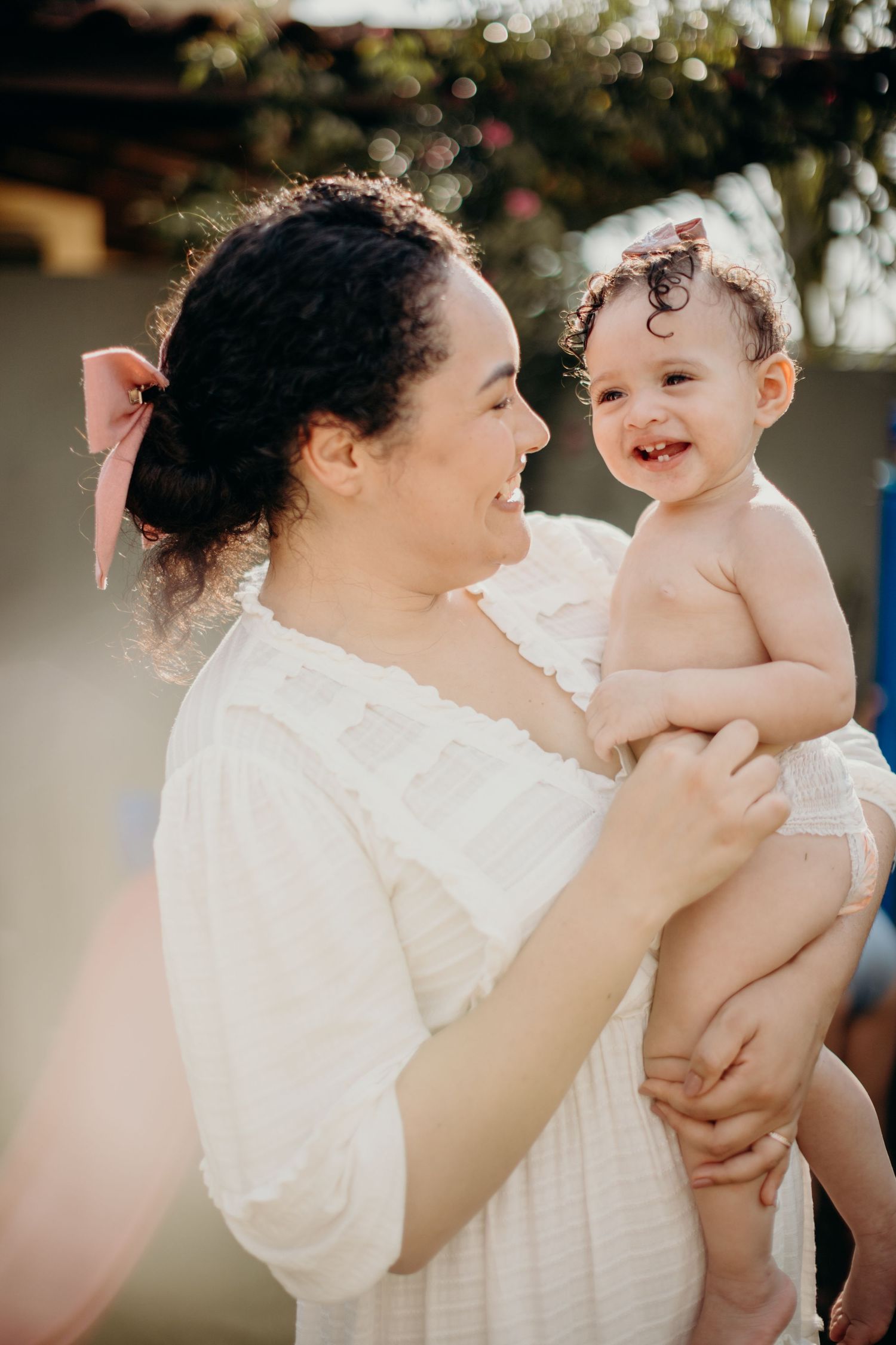 A heartwarming moment of laughter shared between parent and child in white clothing outdoors.