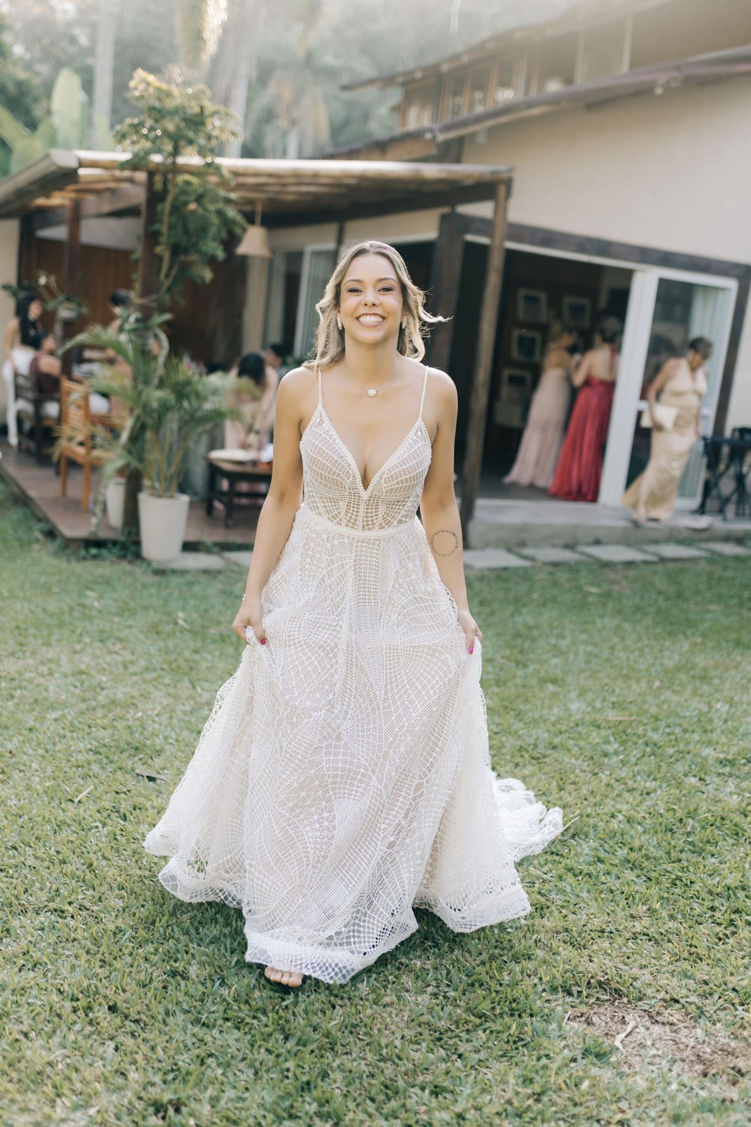 Bride twirling in detailed white lace wedding gown on grass.
