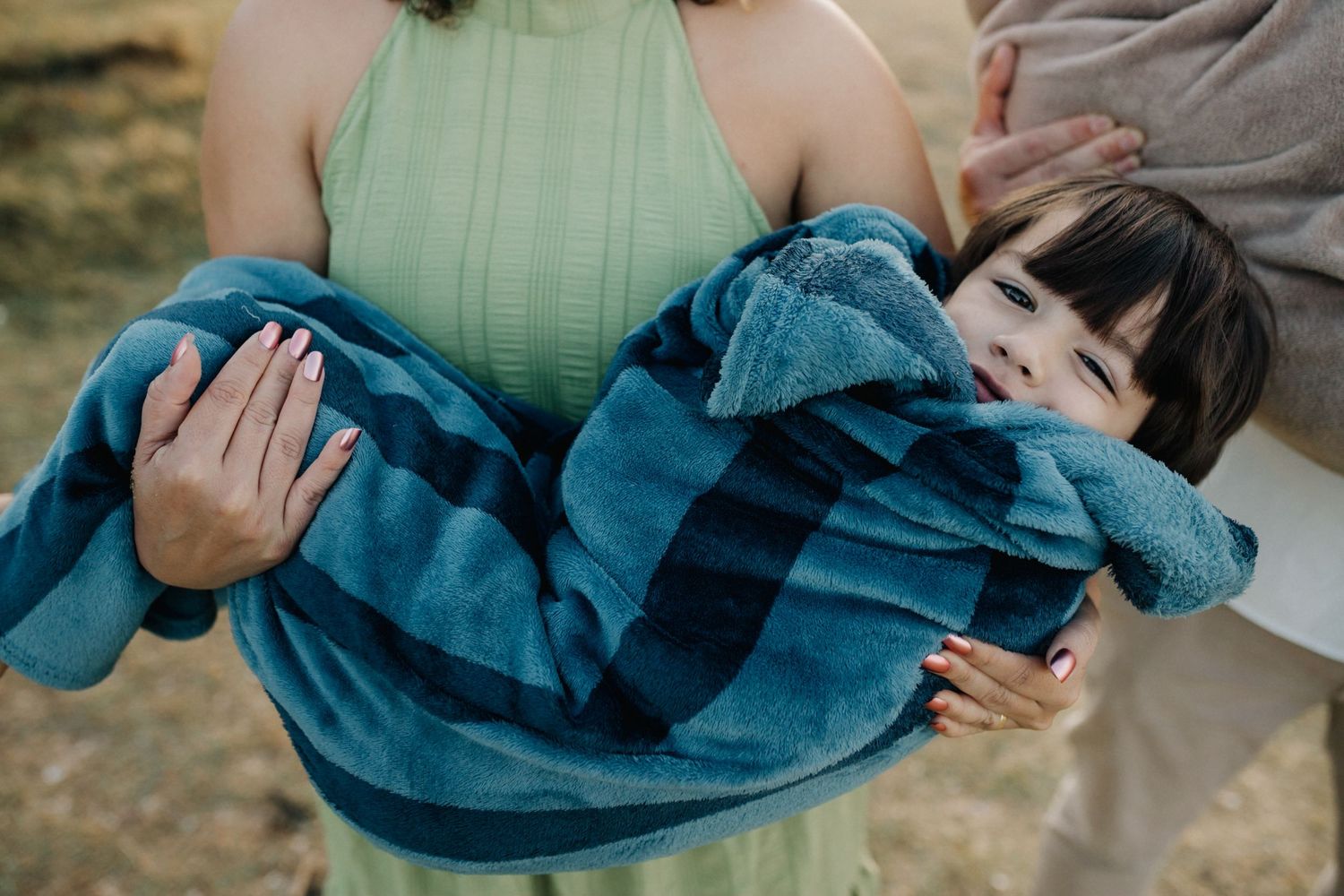 Close-up view of a loving embrace between parent and child wrapped in a blue blanket.