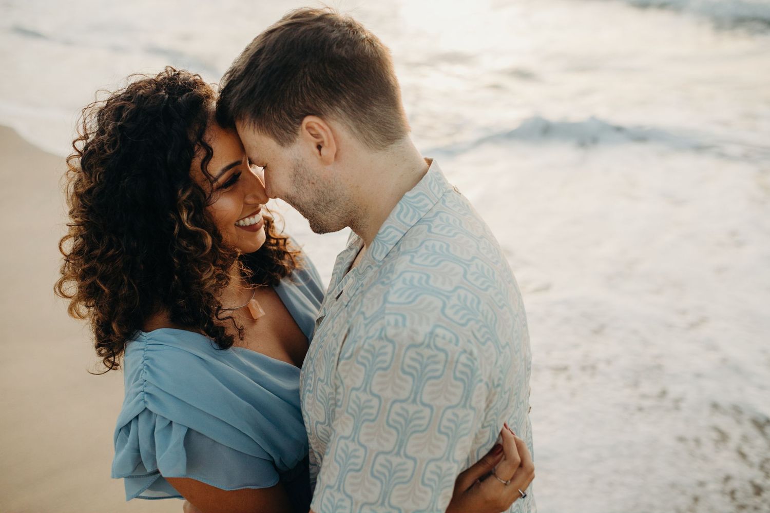 Intimate couple moment captured on sandy beach at sunset.