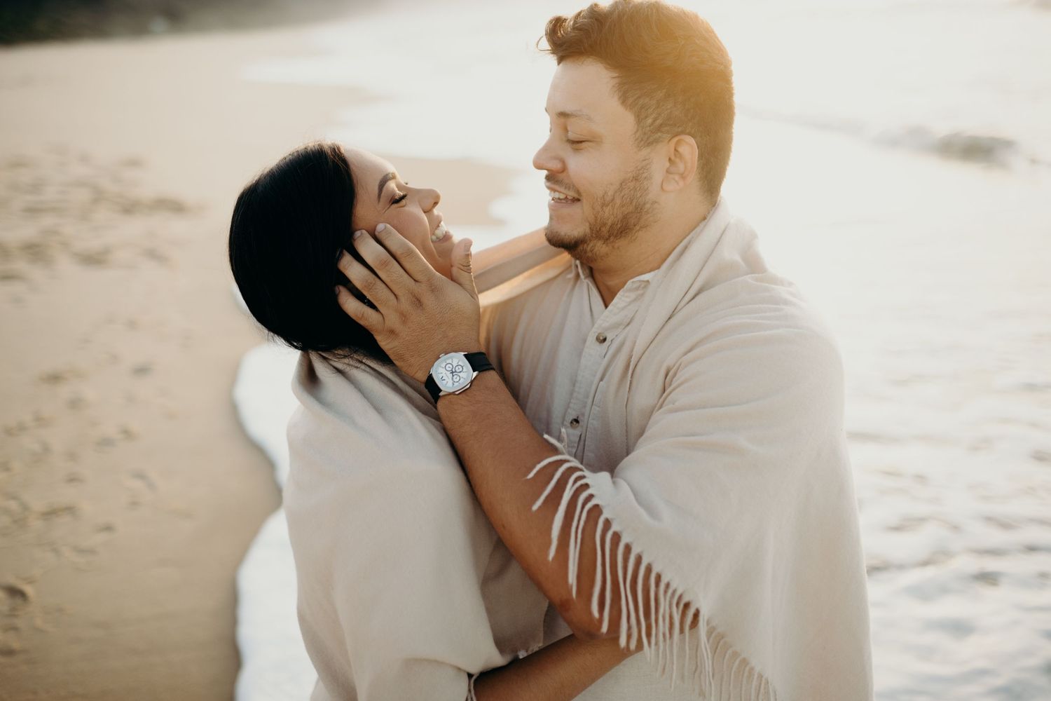 A romantic couple embraces on a sandy beach during sunset in Hawaii, creating a timeless moment.