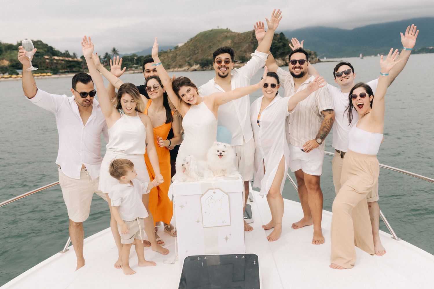 Celebratory group photo of friends and family raising hands during a boat gender reveal party.