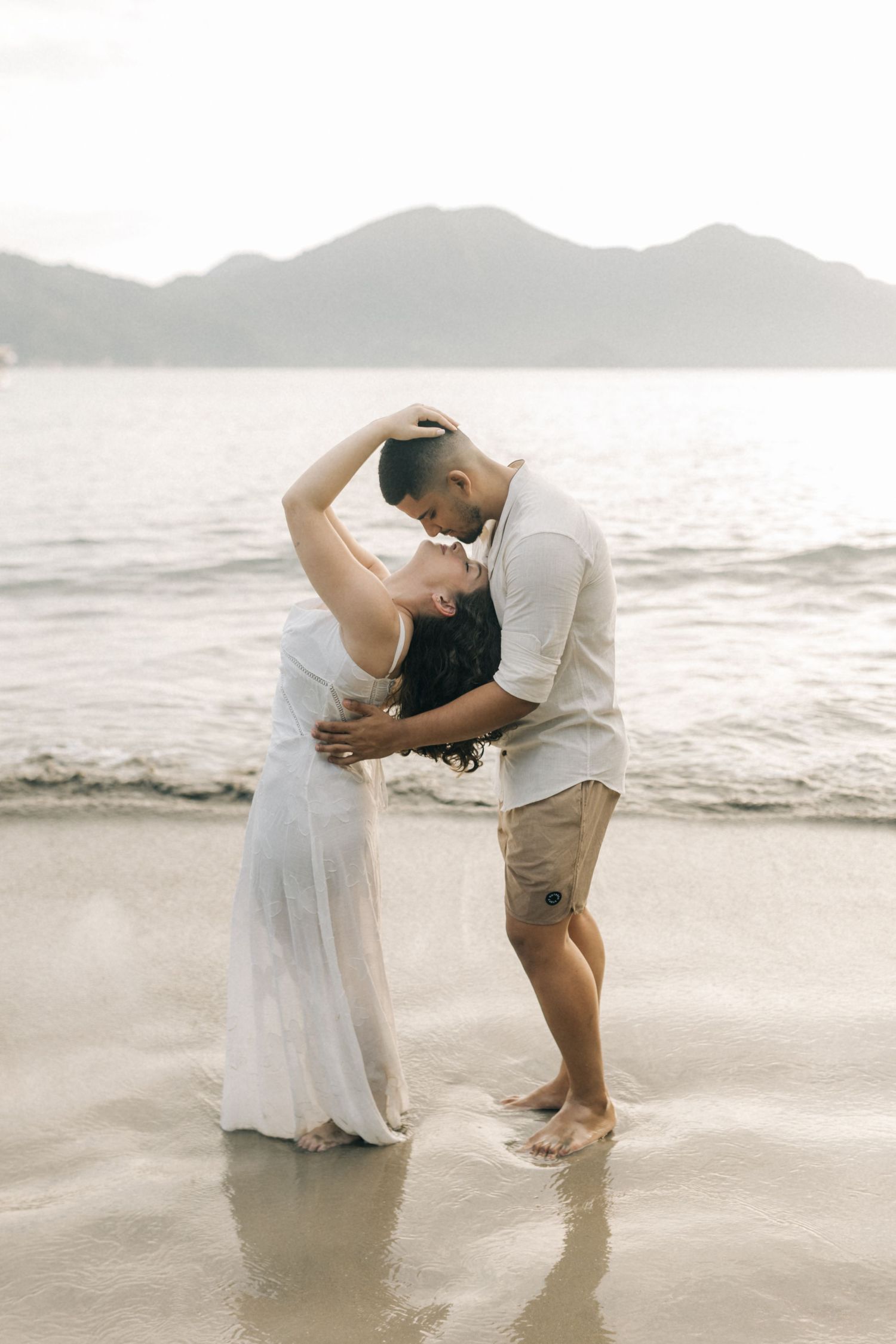 A couple dances in the shallow water during their beach photo session.