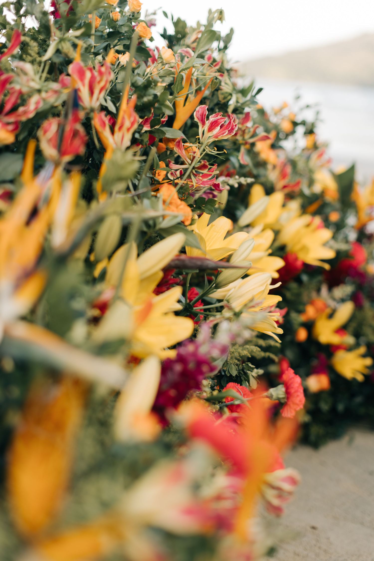 Colorful wedding floral arrangement with yellow and pink blooms in soft focus.