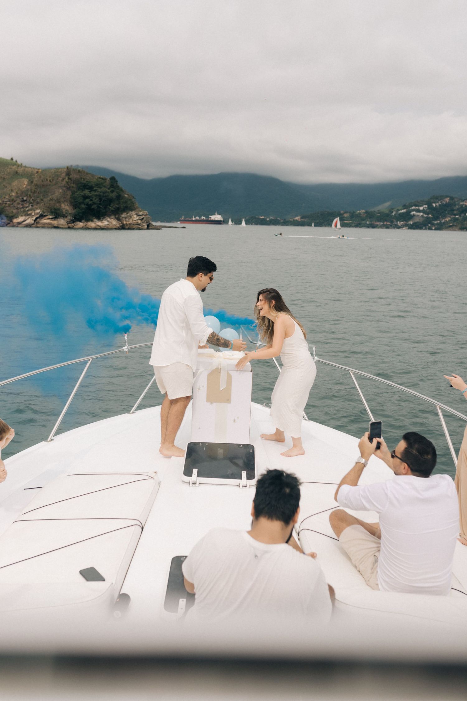 Special moment shared on a yacht's deck with blue smoke and mountains in the distance.