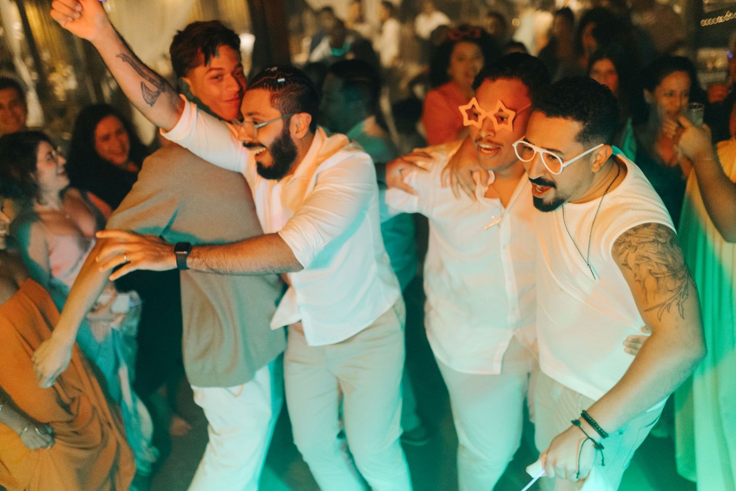 Crowd of party guests dancing and celebrating in casual white attire.
