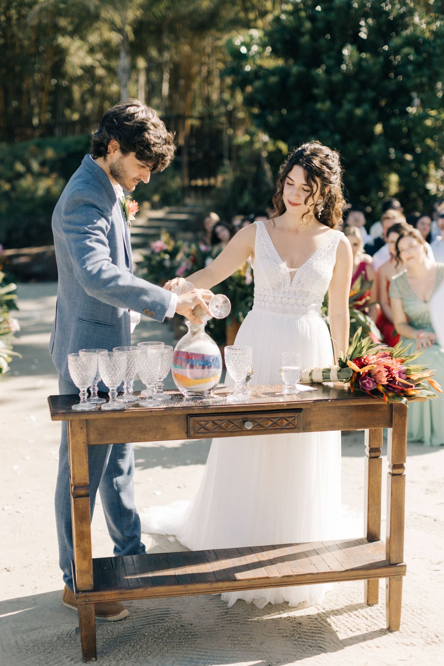 Couple participating in a wedding sand ceremony at an outdoor reception.