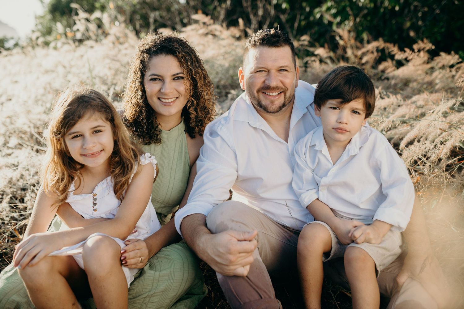 Beautiful outdoor family portrait with everyone coordinated in white and sage green attire.