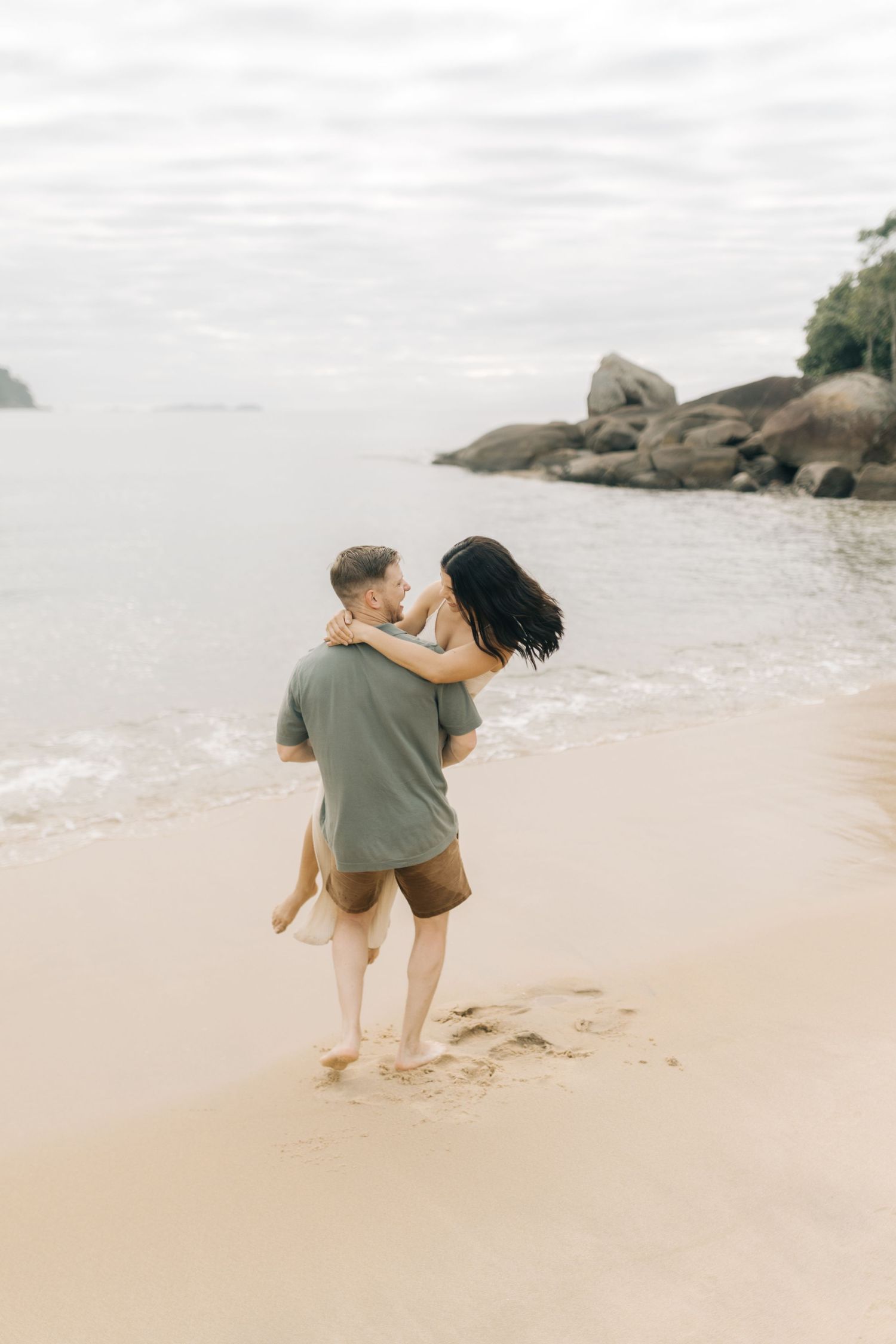 A romantic moment captured on a serene beach as a couple shares an intimate embrace by the water.
