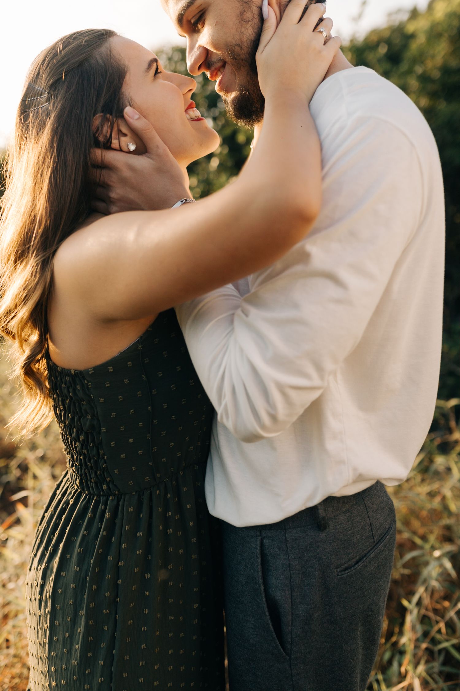 Joyful couple sharing intimate moment during sunset photoshoot.