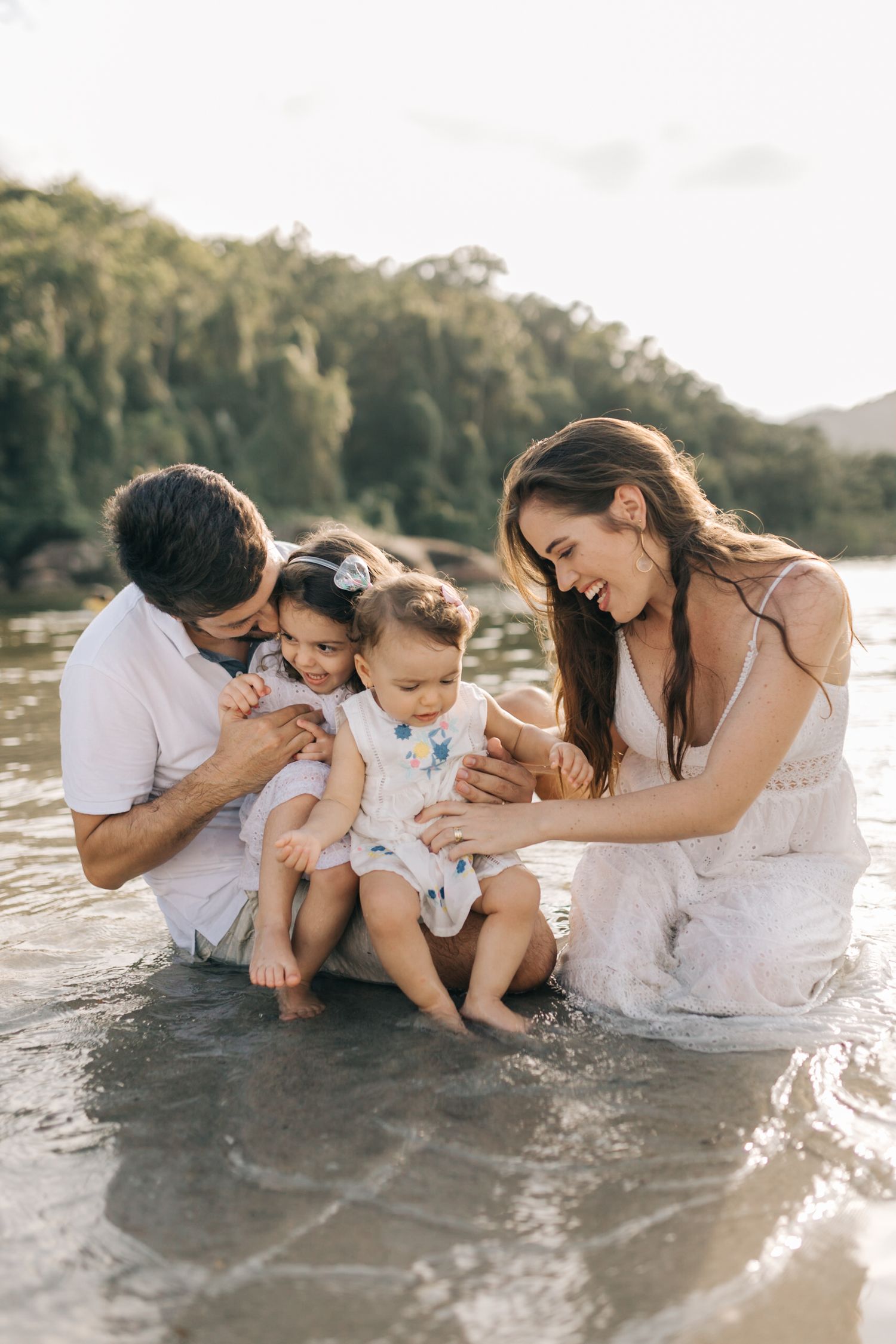 Family sitting in shallow water at sunset enjoying close bonding time.