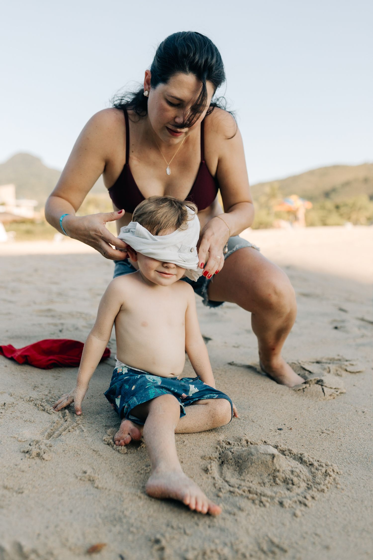 Adult and child enjoying a playful moment on sandy beach during summer day.